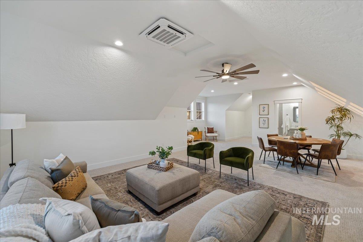 Carpeted living area featuring a textured ceiling, vaulted ceiling, and recessed lighting