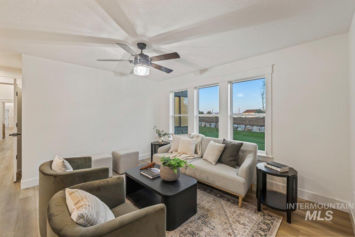 Living area featuring light wood finished floors, ceiling fan, and a textured ceiling