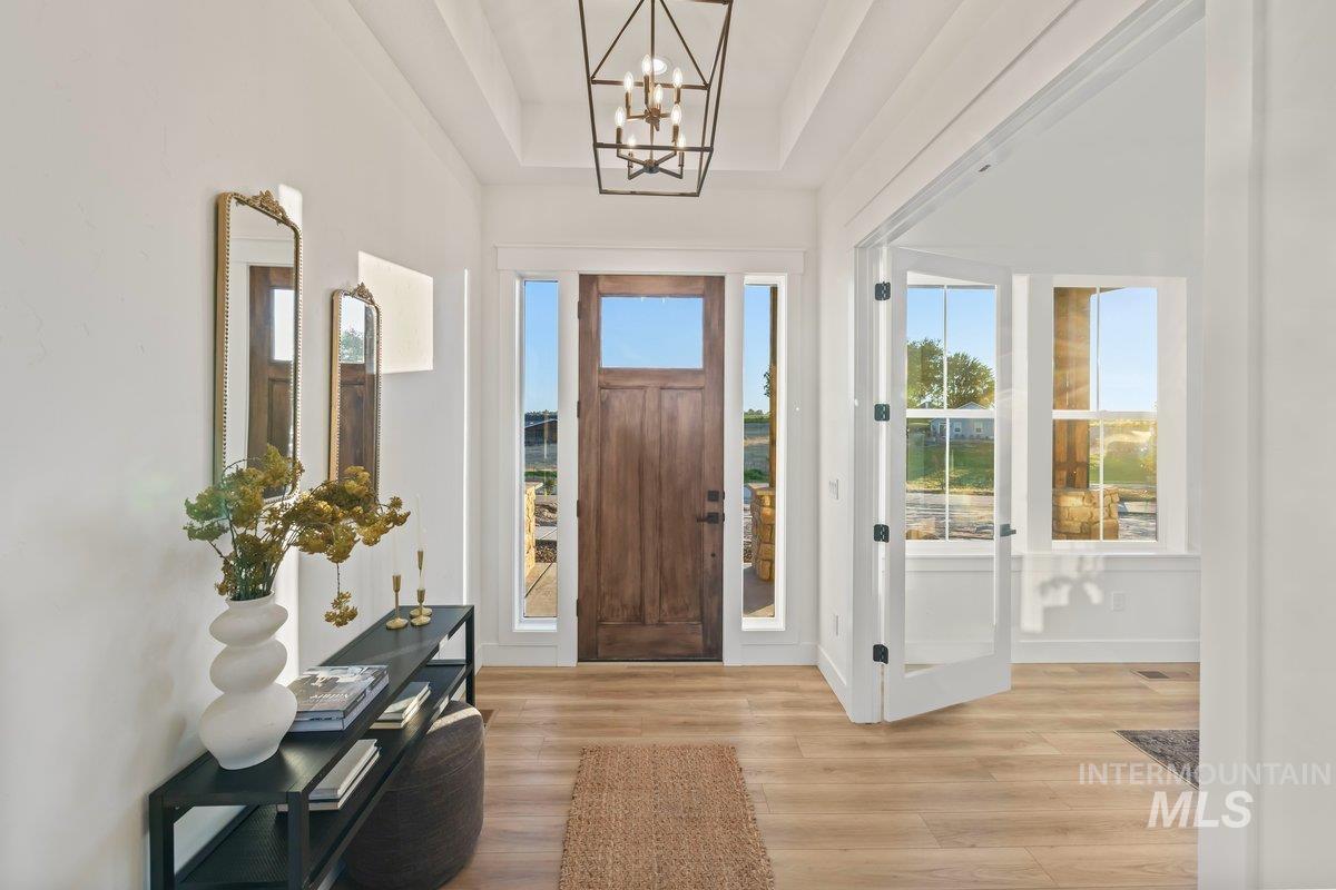 Entryway featuring a chandelier, wood finished floors, and a raised ceiling