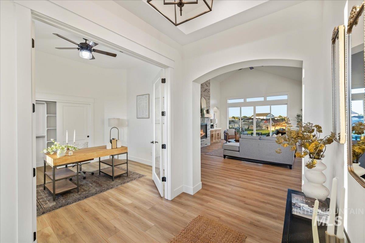 Entrance foyer with light wood-style flooring, a large fireplace, vaulted ceiling, and a ceiling fan