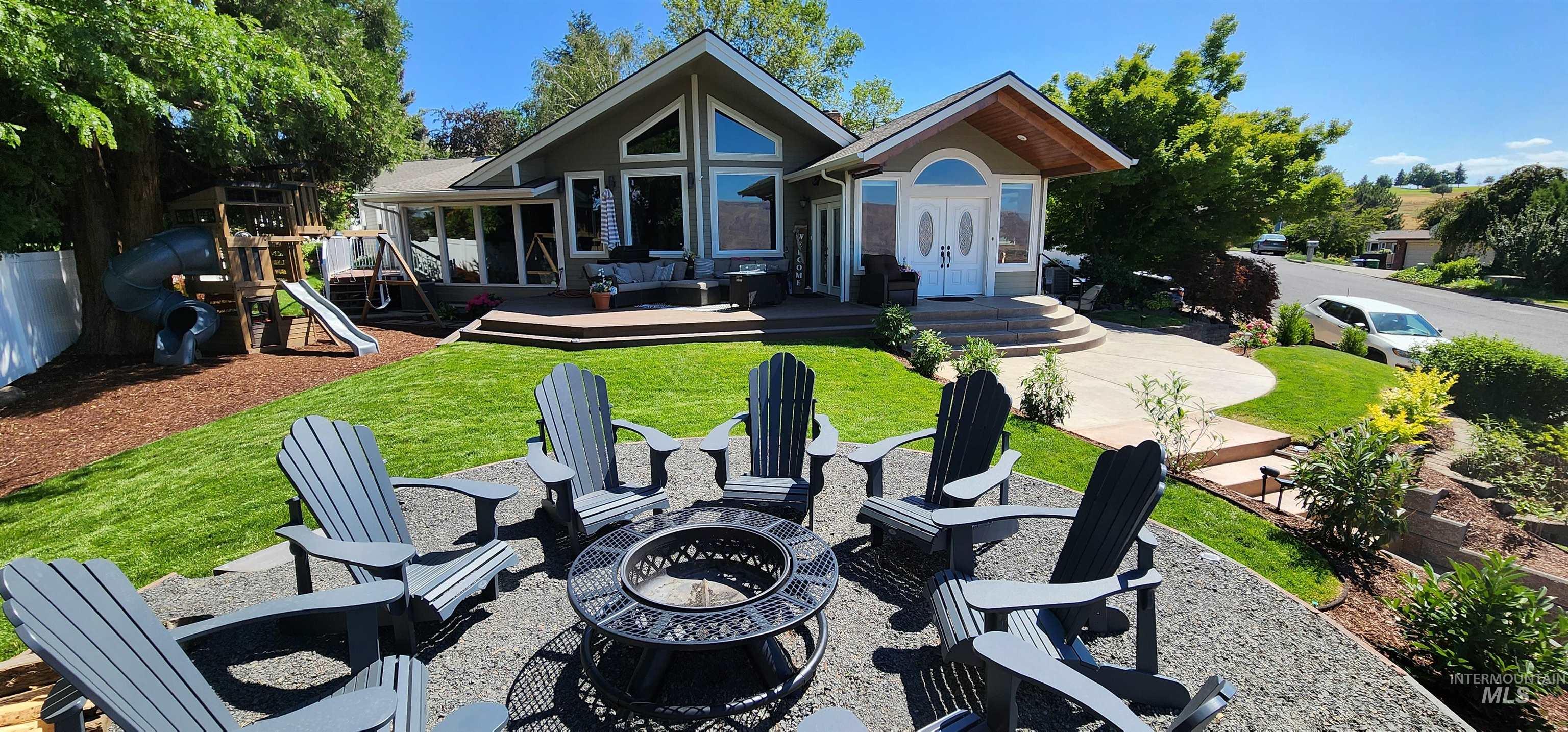Front of property featuring a fire pit, a yard, a patio, a deck, and a playground