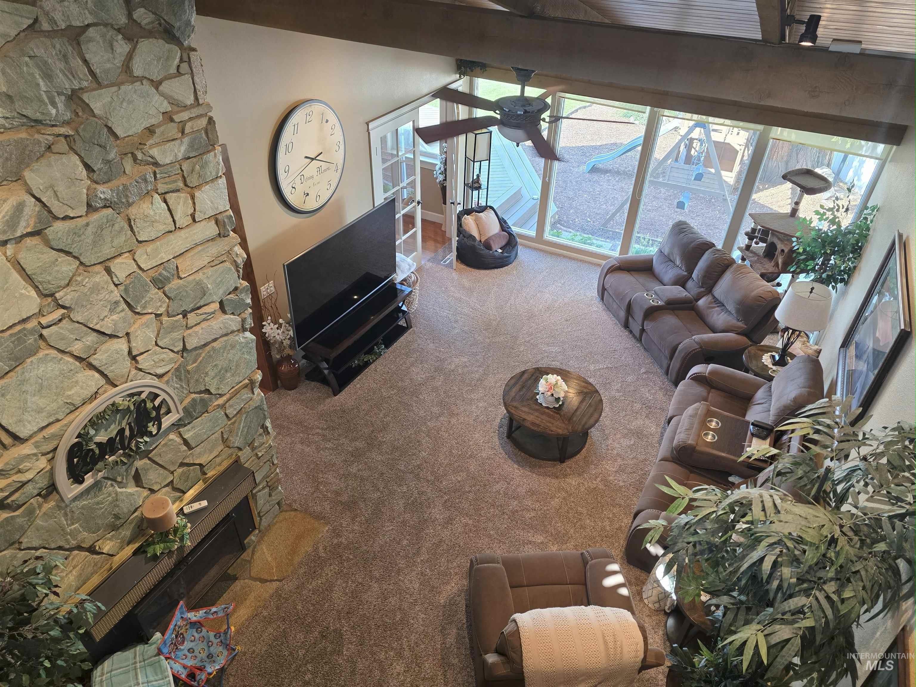 Living area with carpet flooring, a fireplace, and beam ceiling