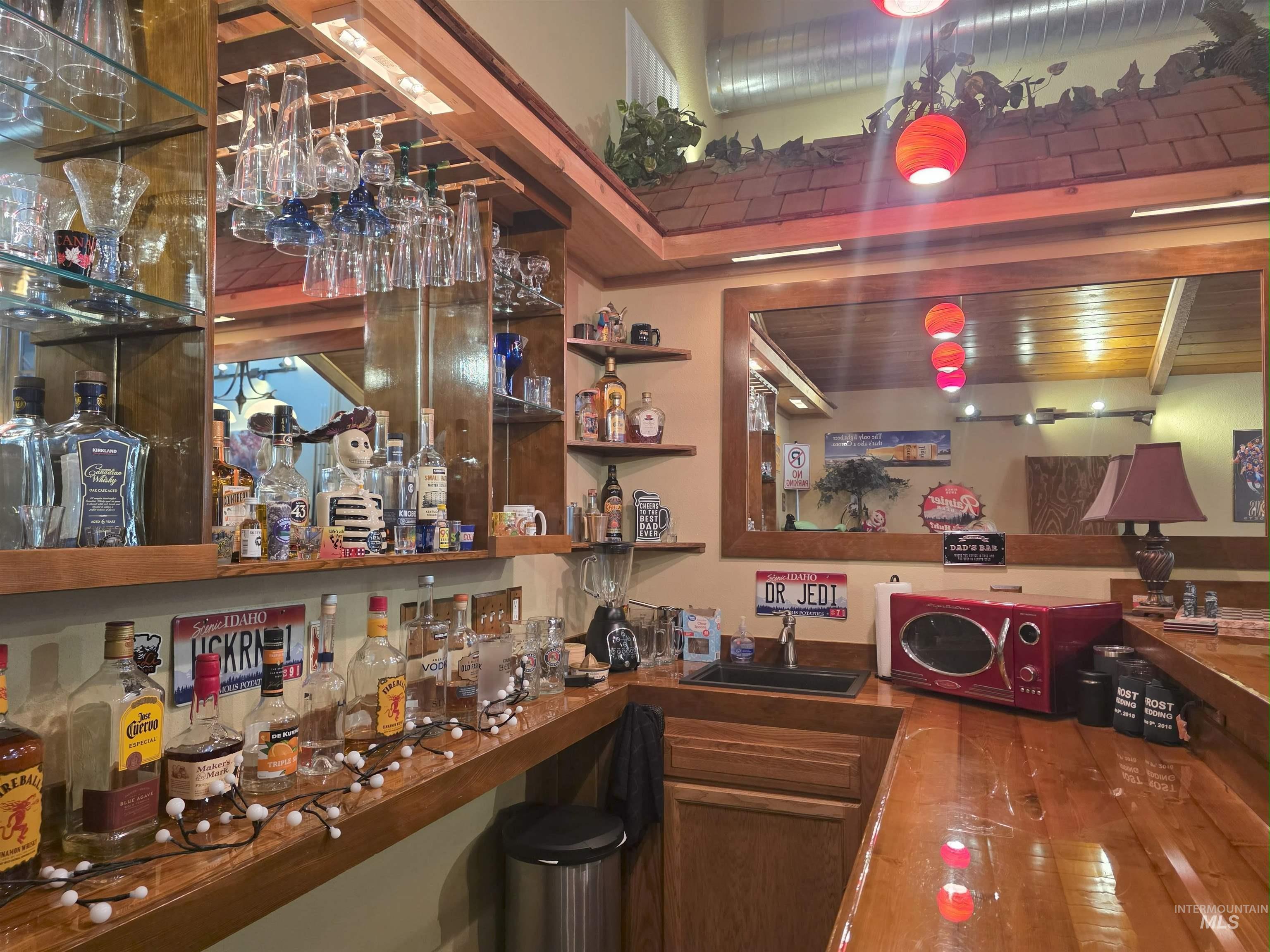 Community bar area with open shelves, wood finished floors, and dark countertops