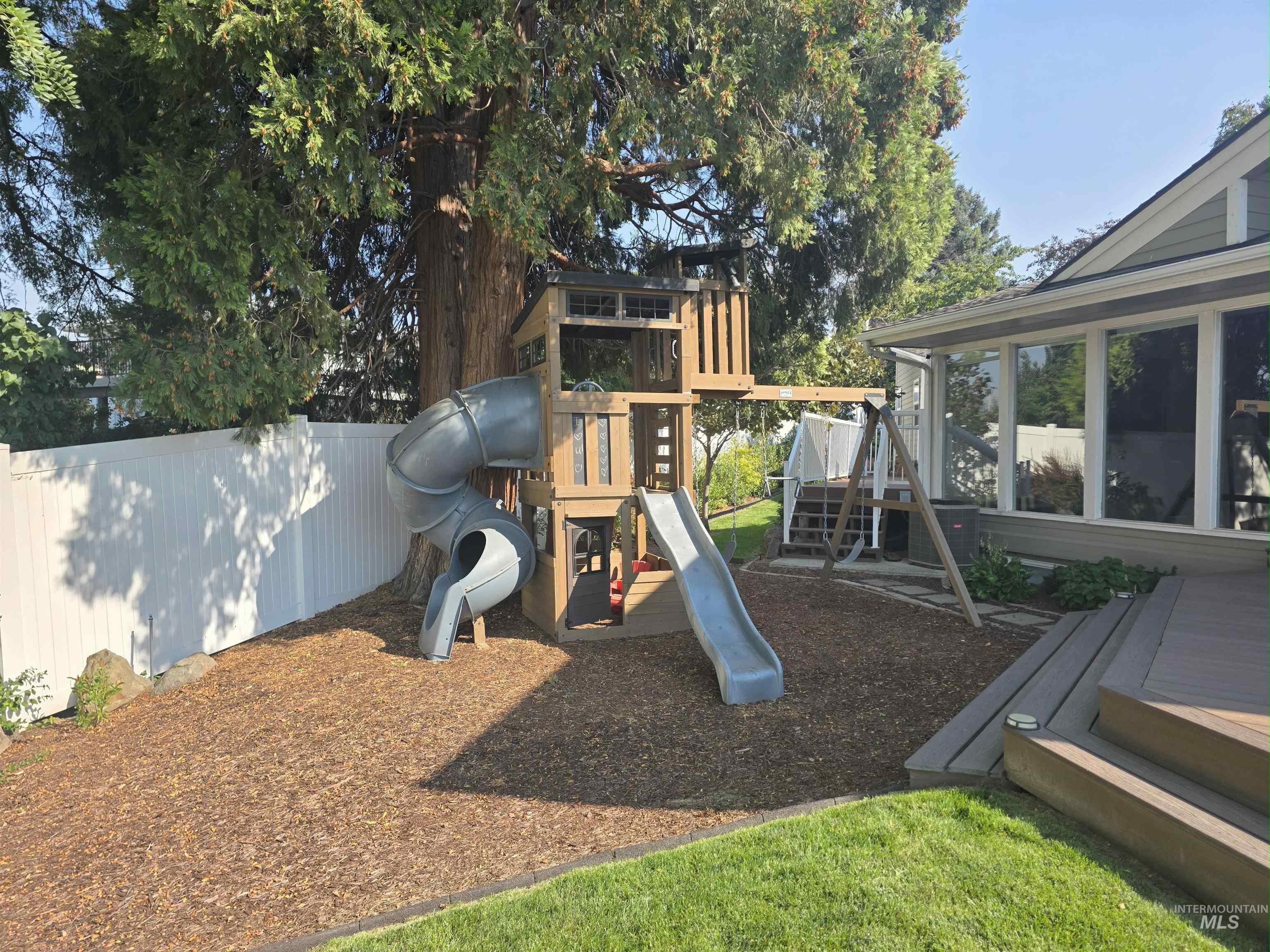 View of playground featuring a deck and a sunroom