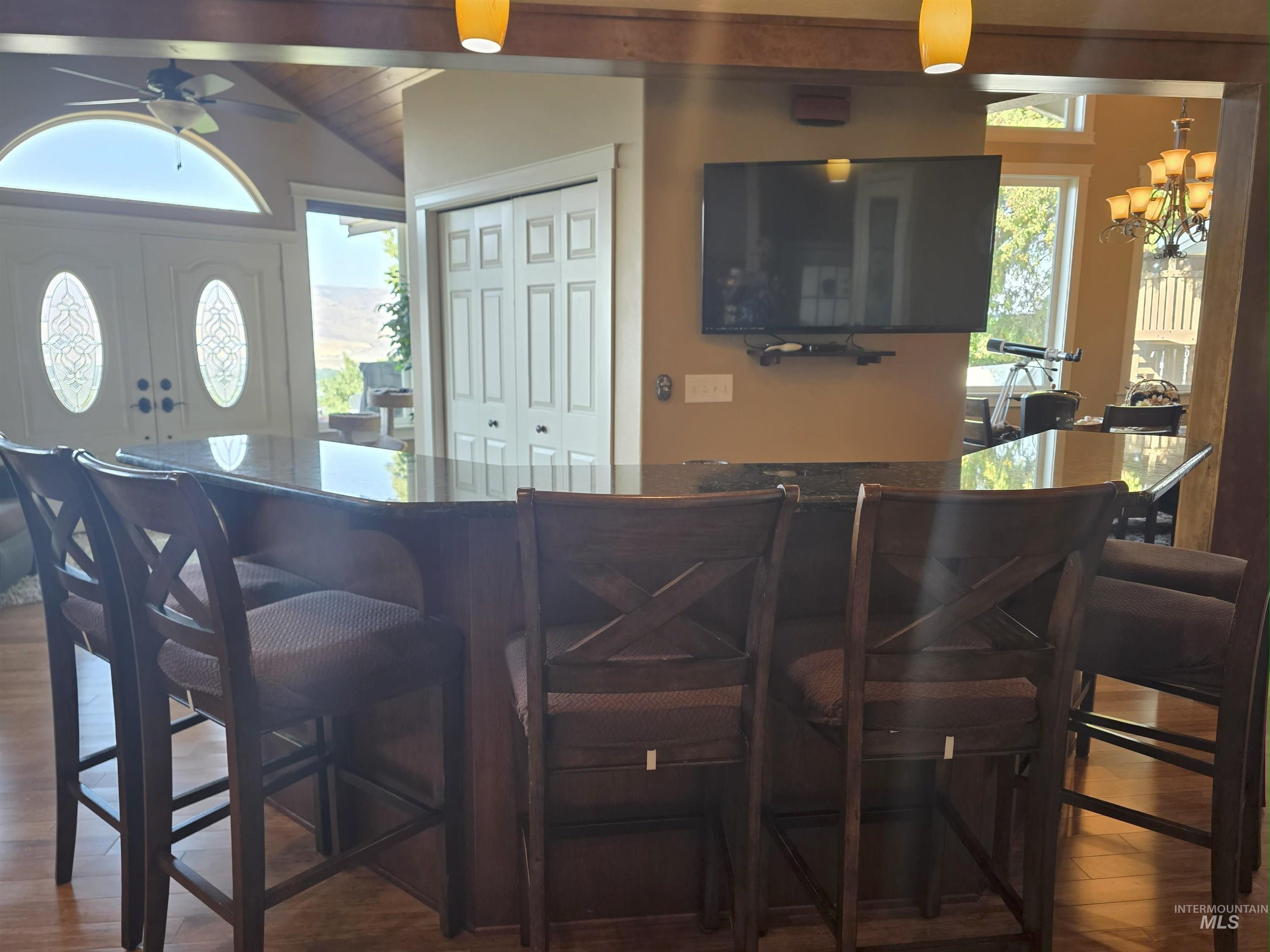 Bar area featuring dark wood finished floors, dark brown cabinets, a chandelier, and a ceiling fan