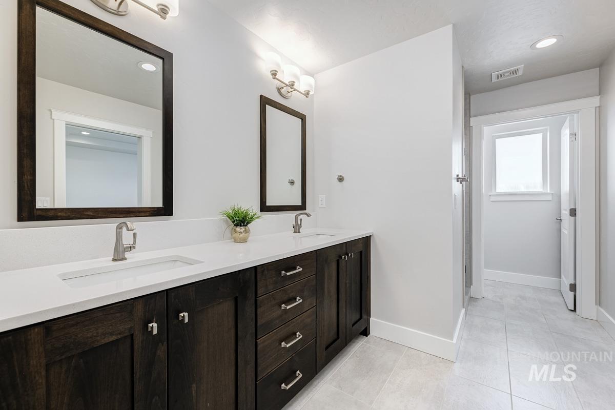 Full bath featuring double vanity, light tile patterned flooring, and recessed lighting