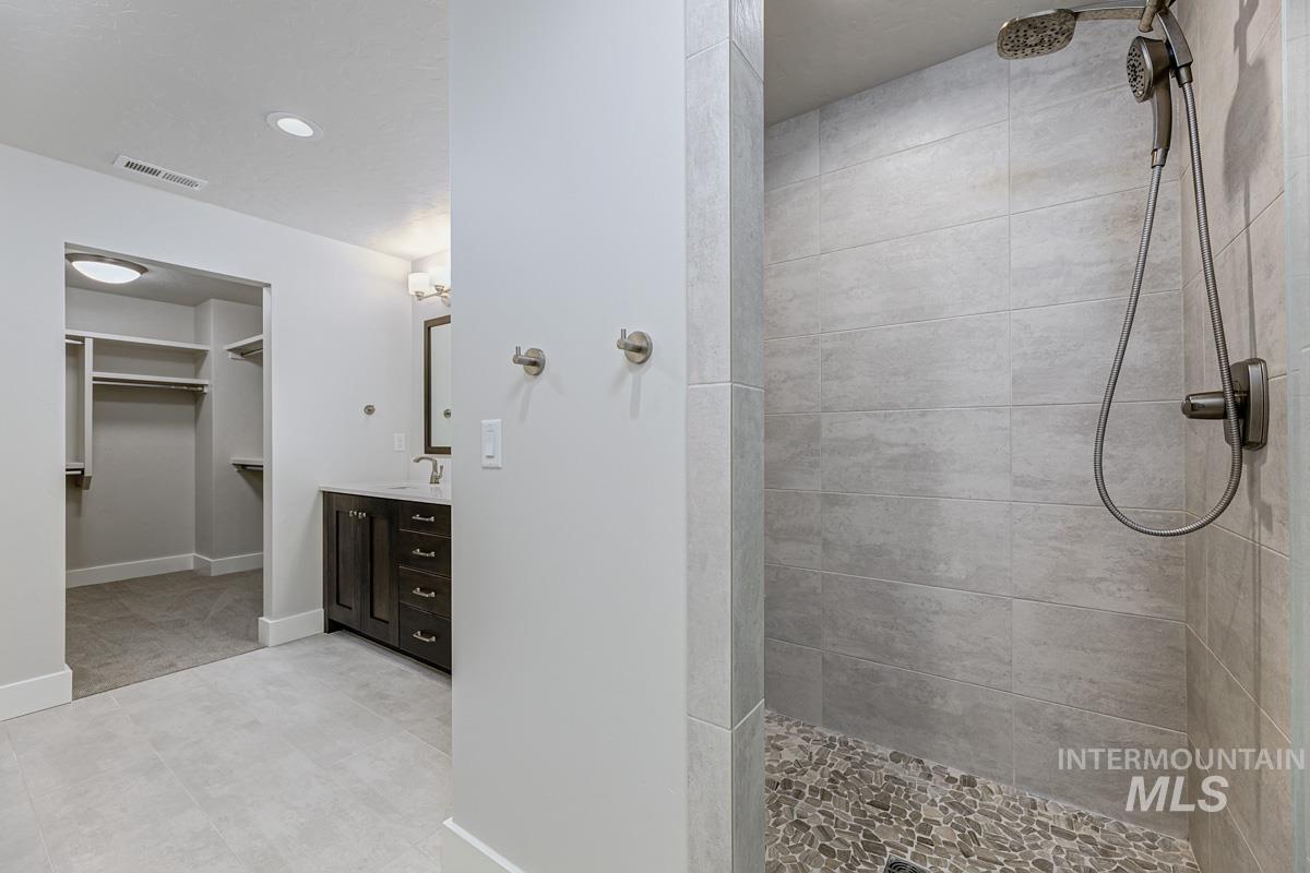 Bathroom with vanity, walk in shower, a walk in closet, and recessed lighting