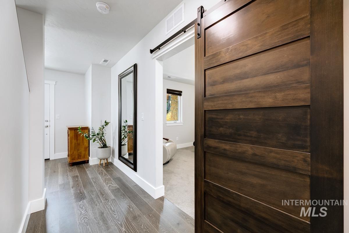 Hallway with a barn door and wood finished floors