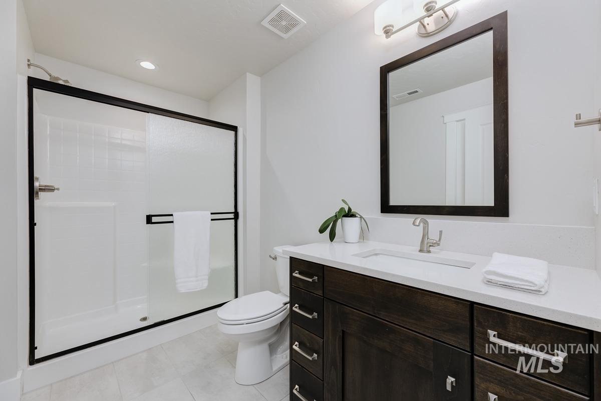 Bathroom with vanity, a shower stall, light tile patterned floors, and recessed lighting