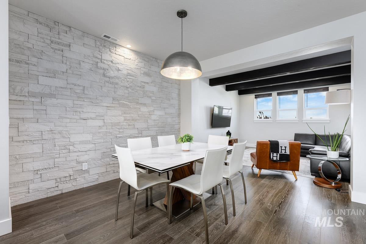 Dining room with dark wood-type flooring and beam ceiling