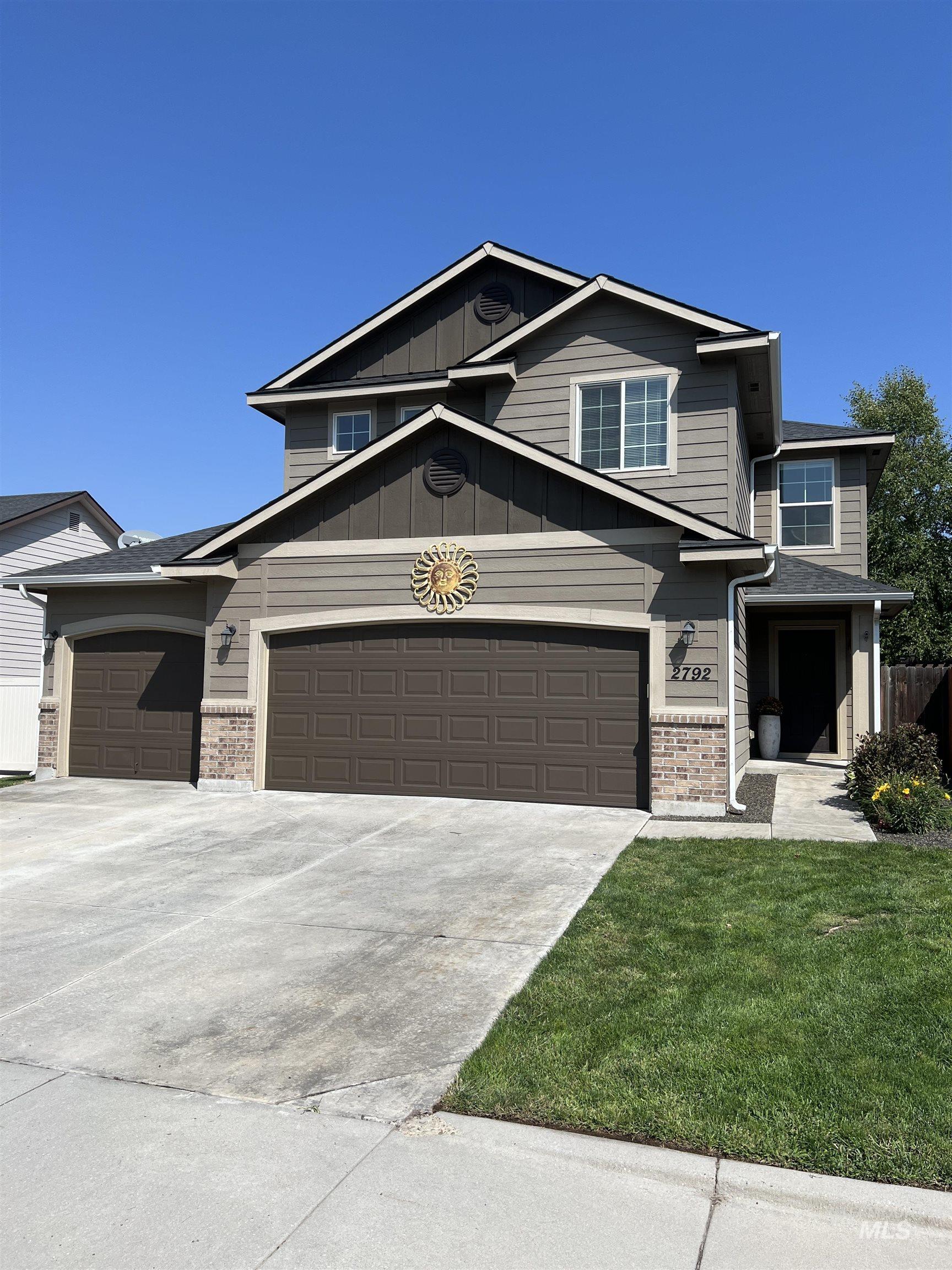 View of front facade featuring board and batten siding, driveway, and brick siding
