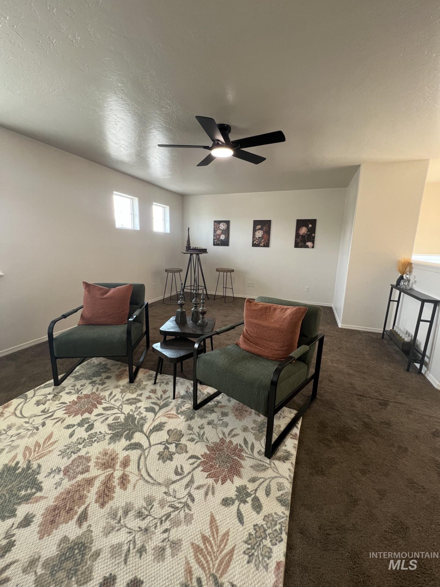 Living area with a textured ceiling, carpet flooring, and ceiling fan