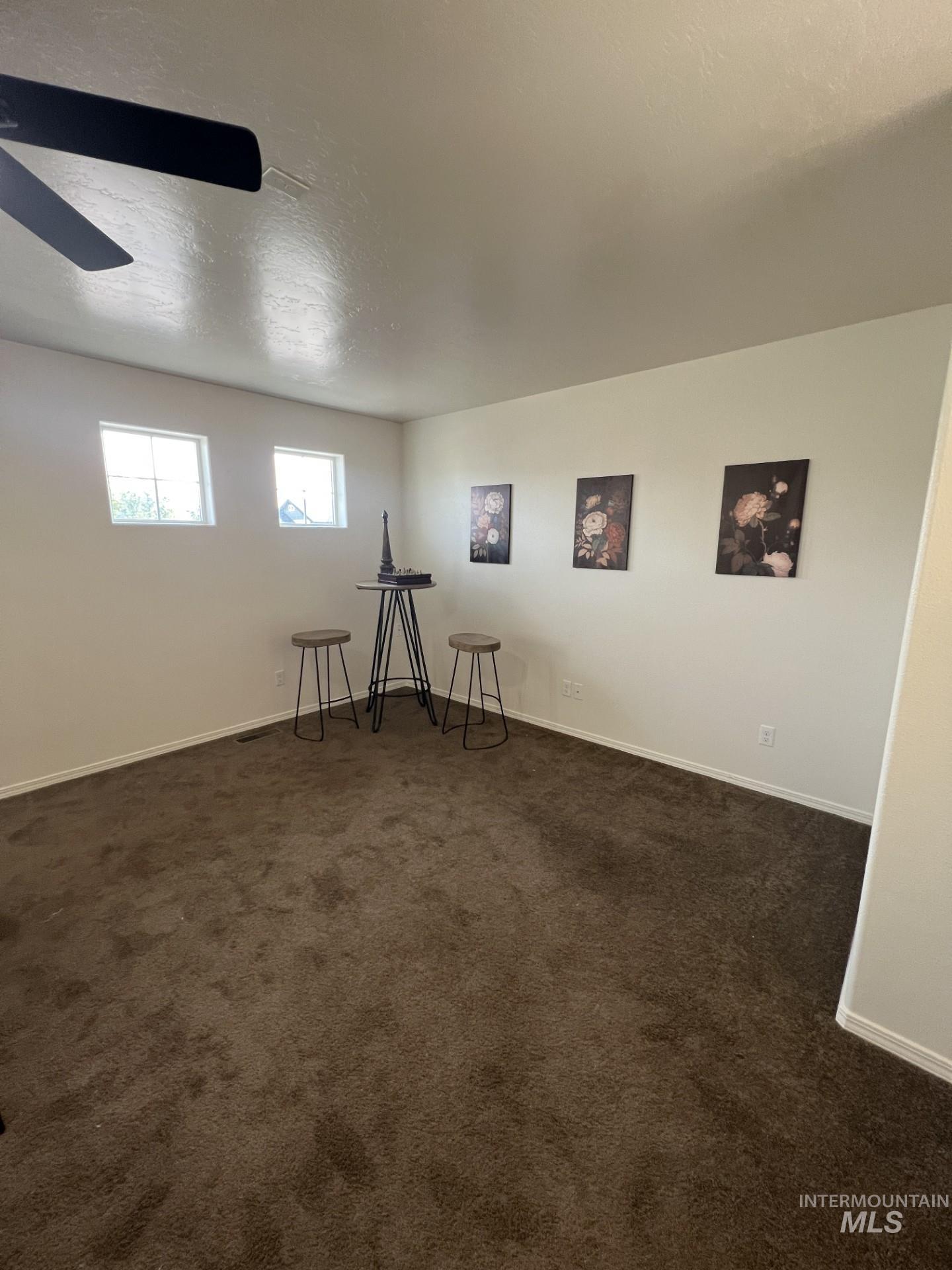 Spare room with a textured ceiling and dark colored carpet