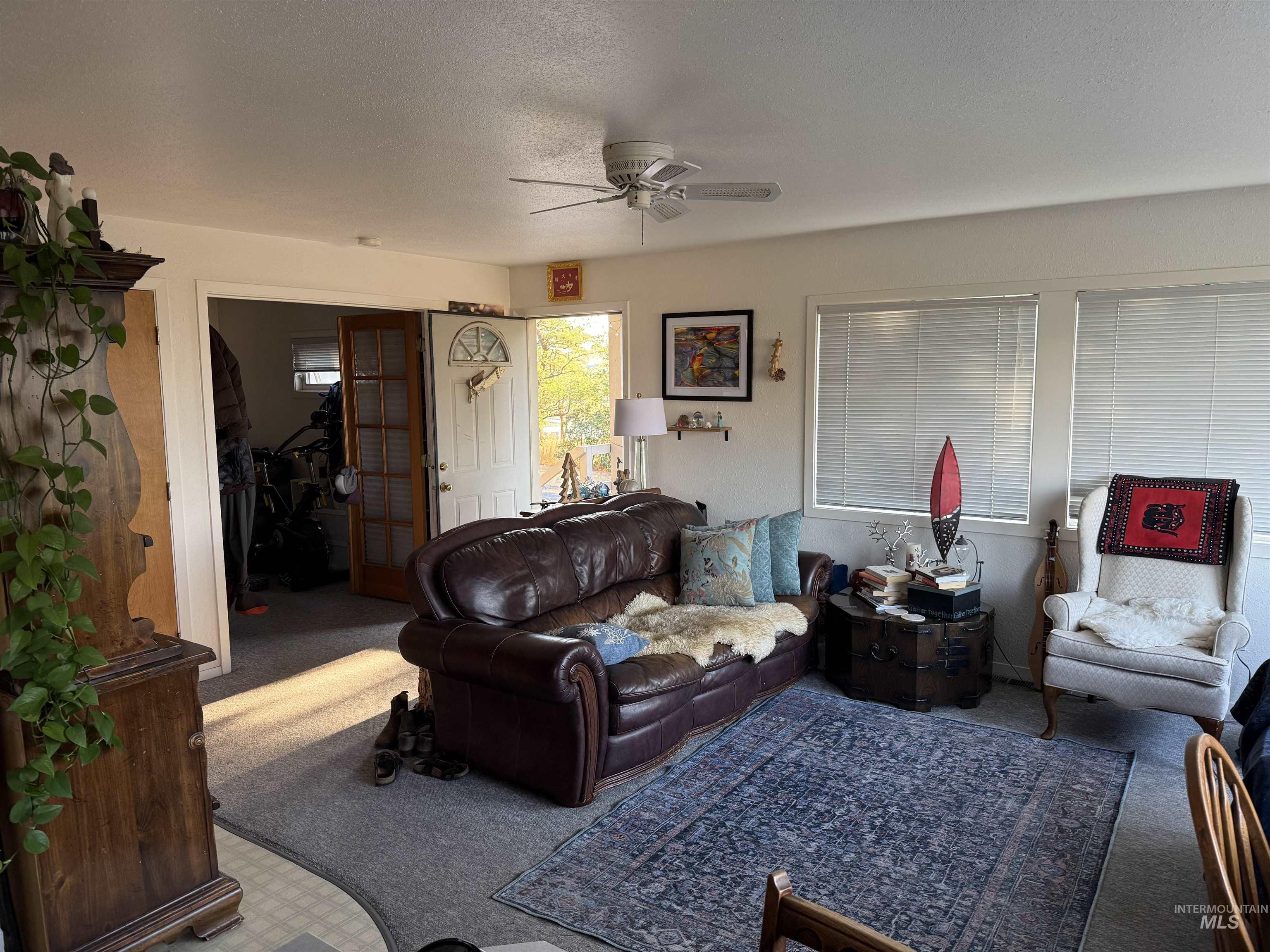 Living area with carpet, ceiling fan, and a textured ceiling