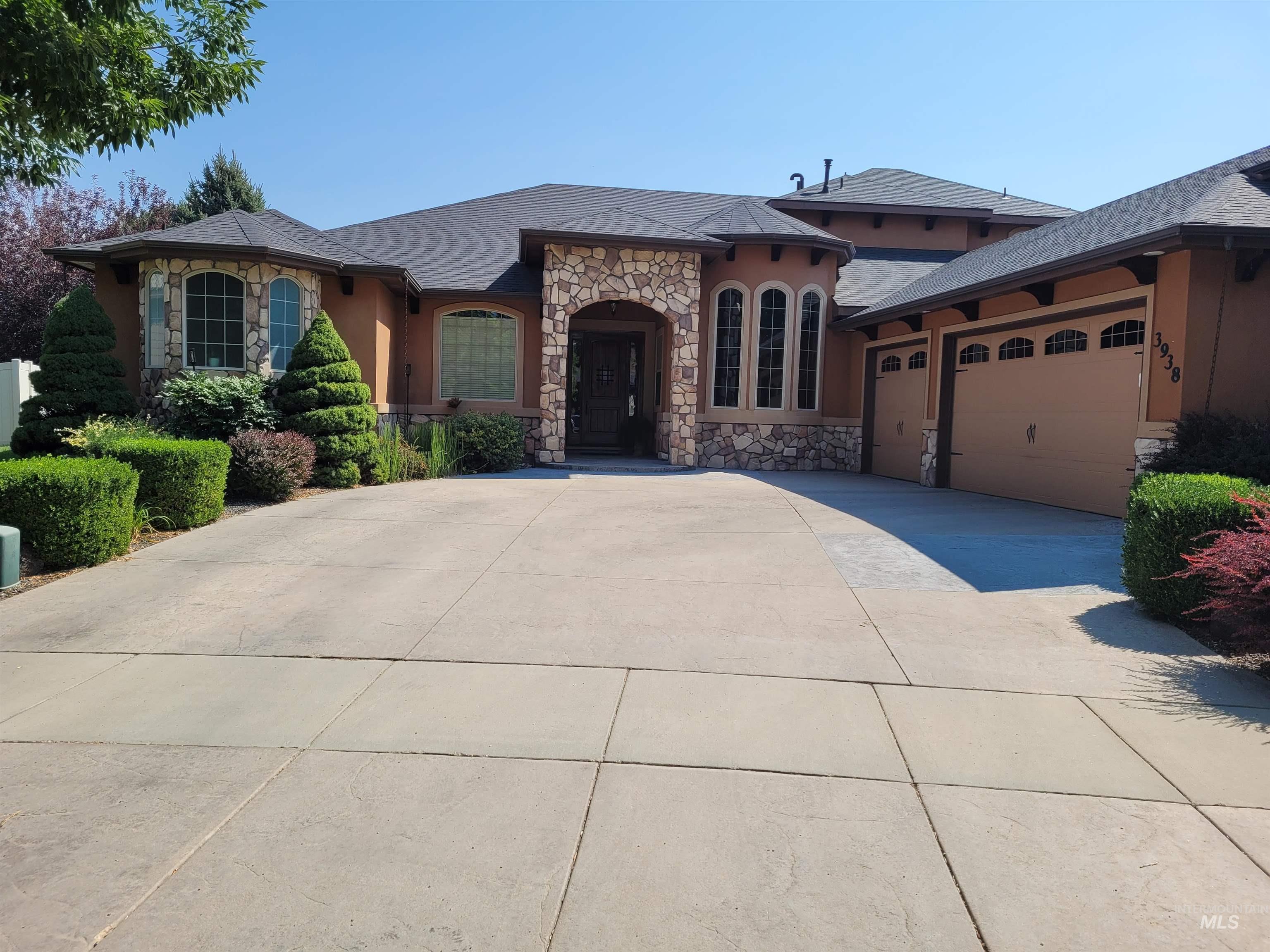View of front of home featuring stone siding, an attached garage, stucco siding, concrete driveway, and roof with shingles