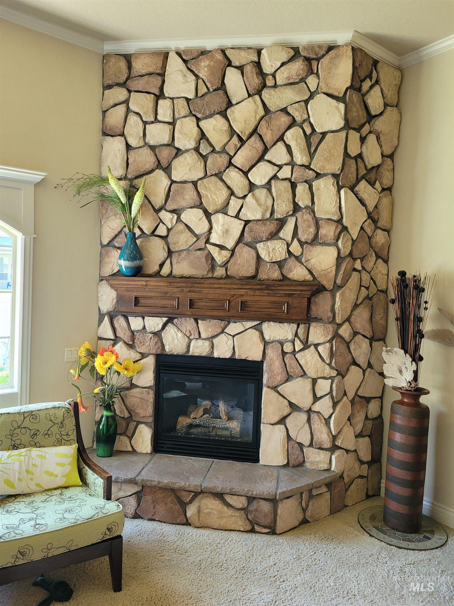 Detailed view of crown molding, a stone fireplace, and carpet