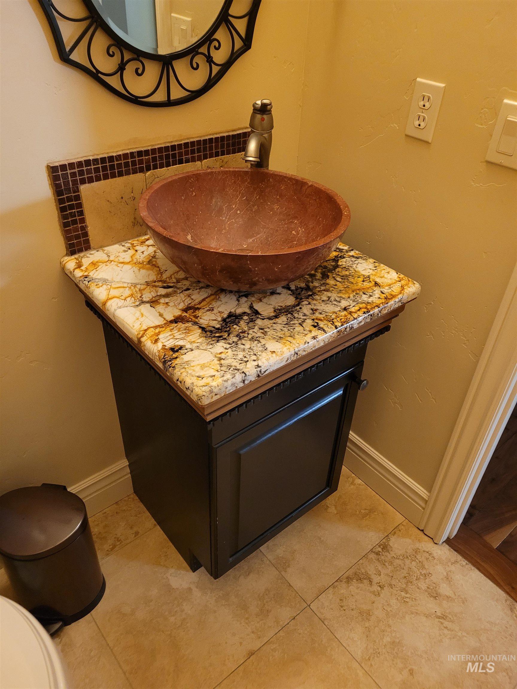 Bathroom with vanity, light tile patterned floors, and a textured wall