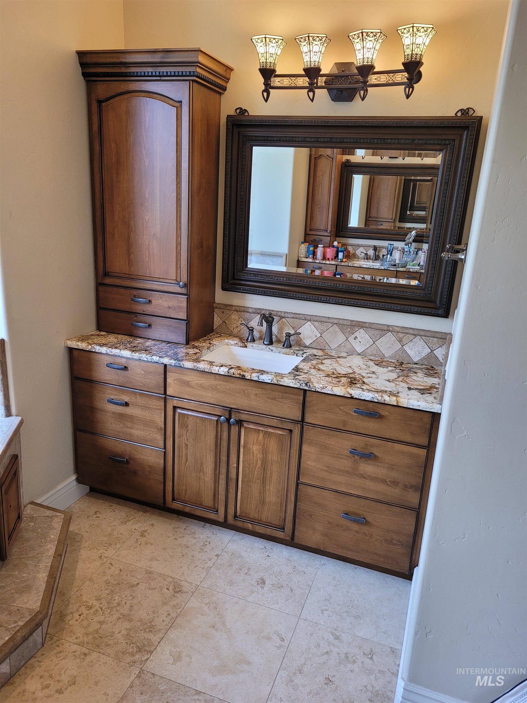 Bathroom featuring vanity, backsplash, and light tile patterned floors