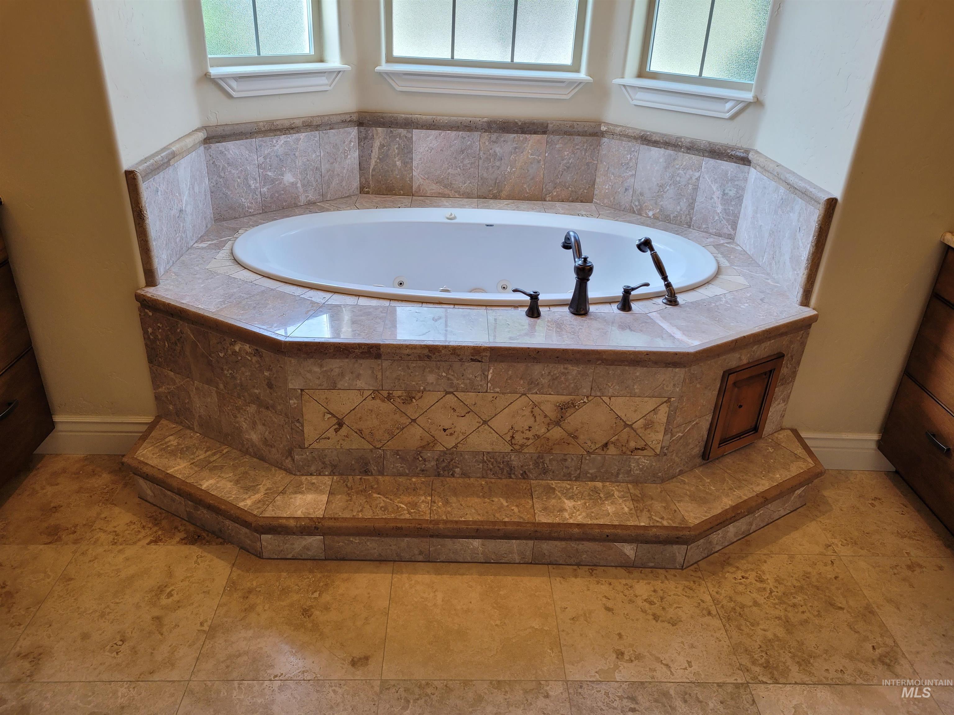 Full bathroom featuring a tub with jets and healthy amount of natural light
