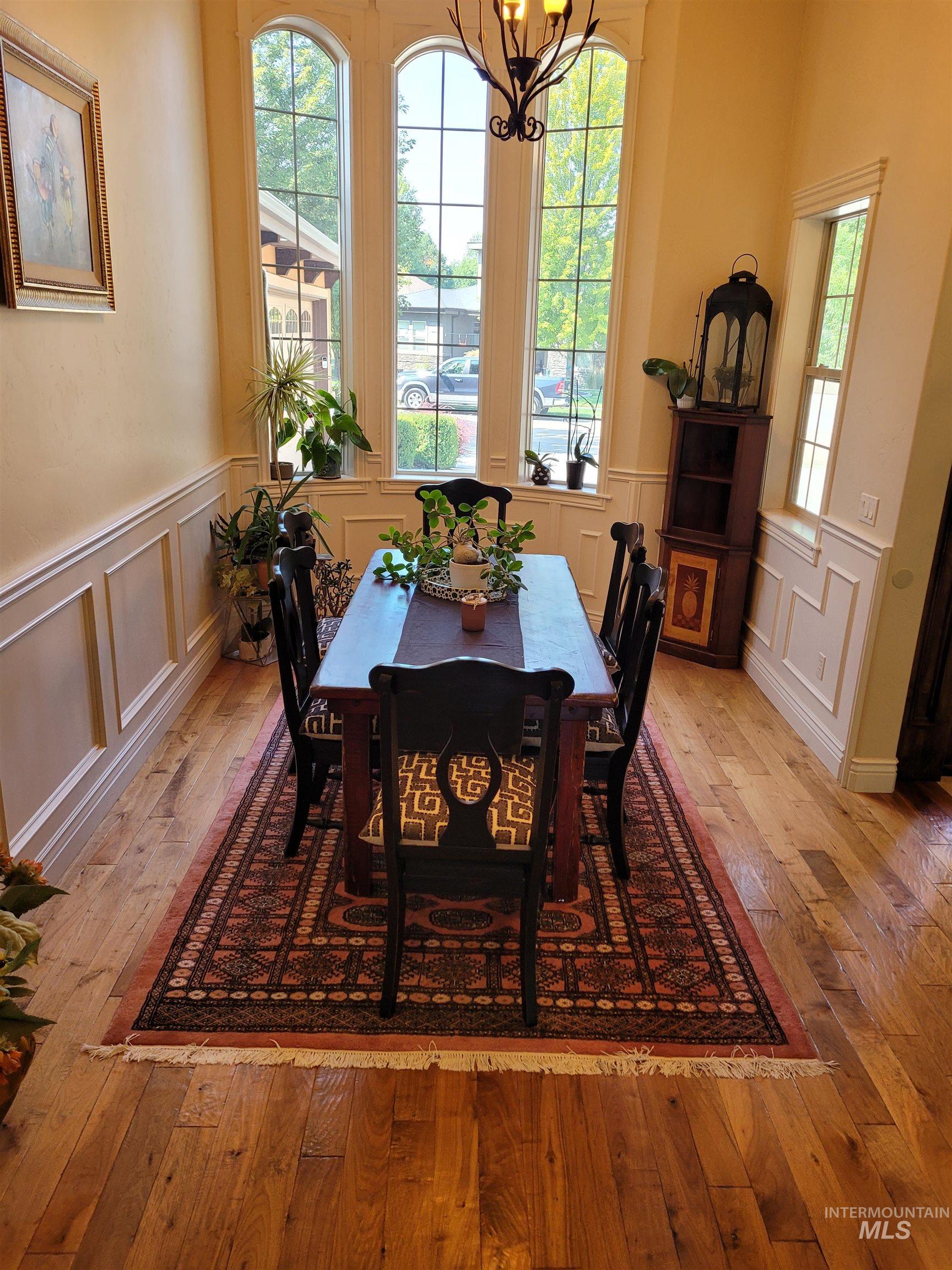 Dining room featuring light wood-type flooring, a chandelier, and a decorative wall