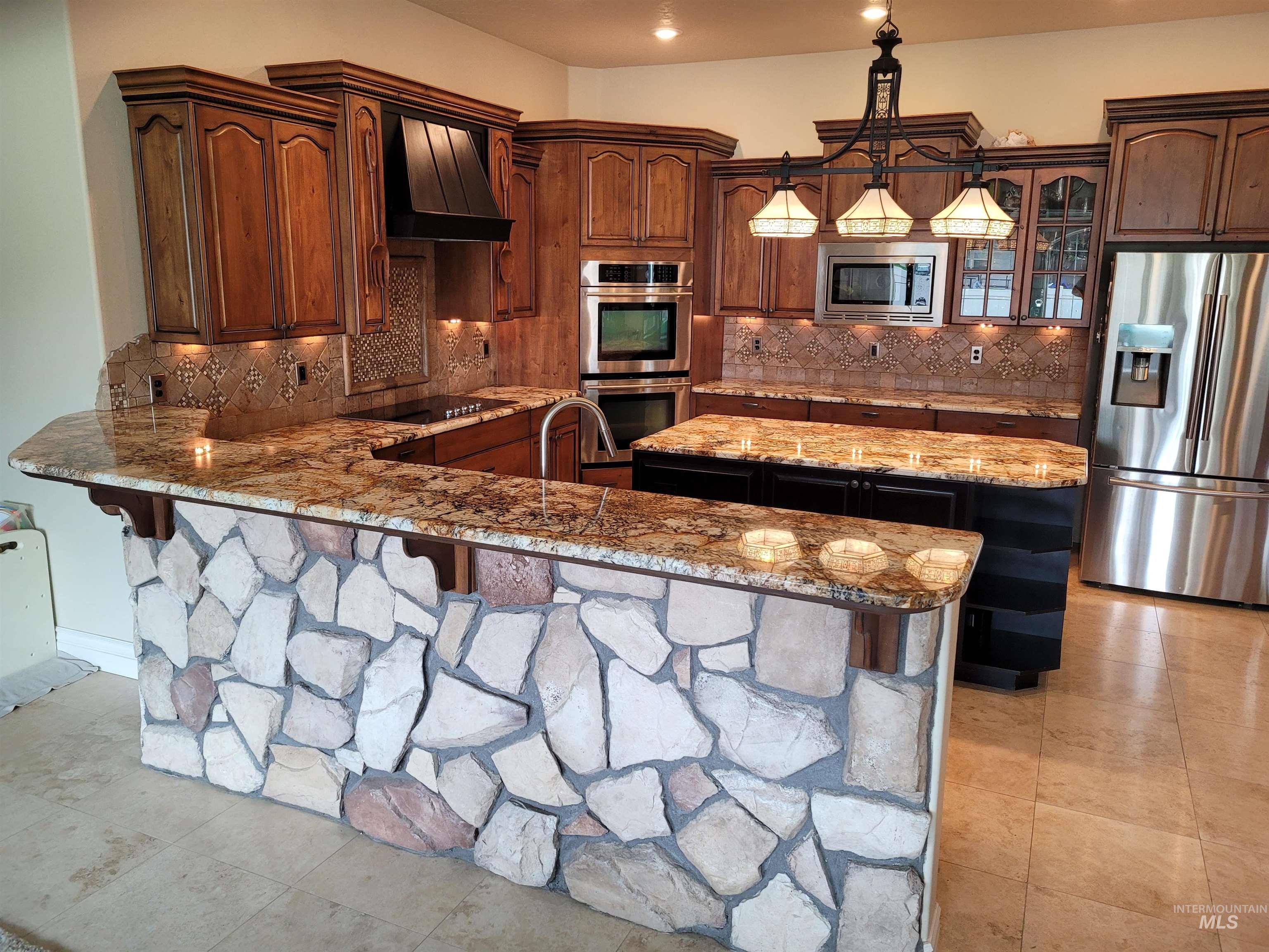 Kitchen featuring a kitchen island, stainless steel appliances, a breakfast bar area, and light stone counters