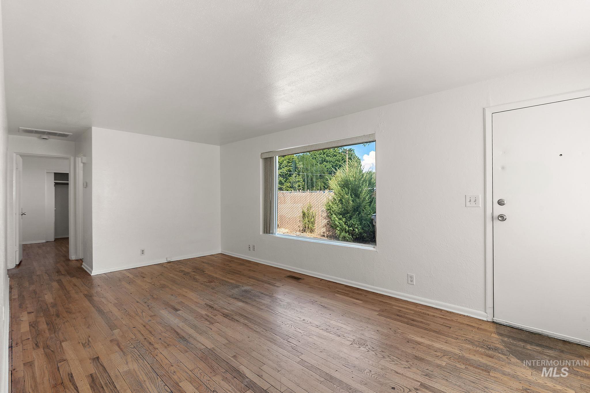 Unfurnished living room with hardwood / wood-style flooring and baseboards