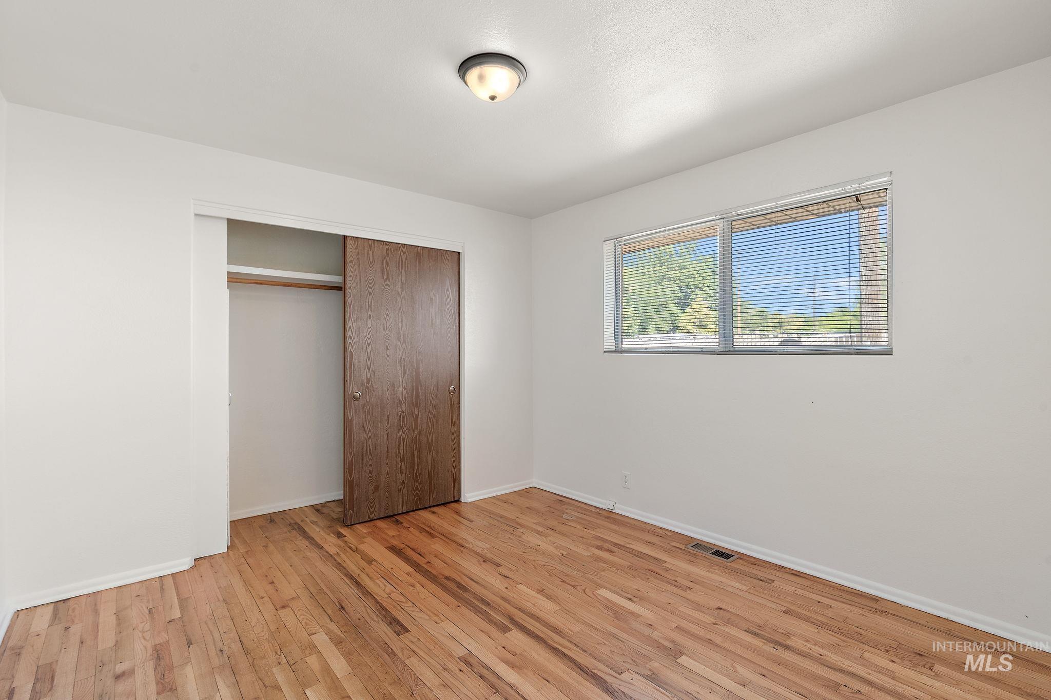 Unfurnished bedroom with light wood-type flooring and a closet