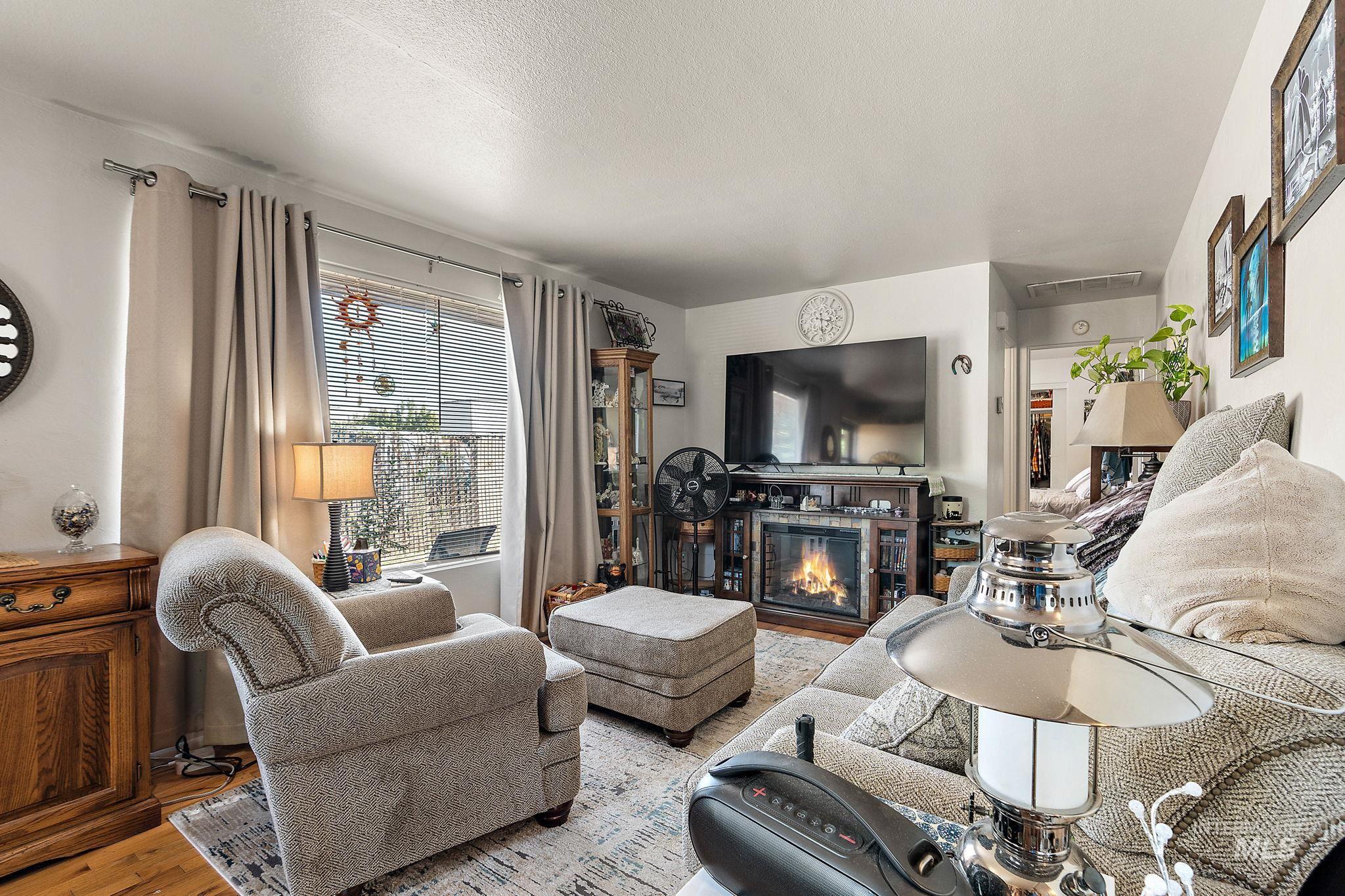 Living area featuring wood finished floors, a glass covered fireplace, and a textured ceiling