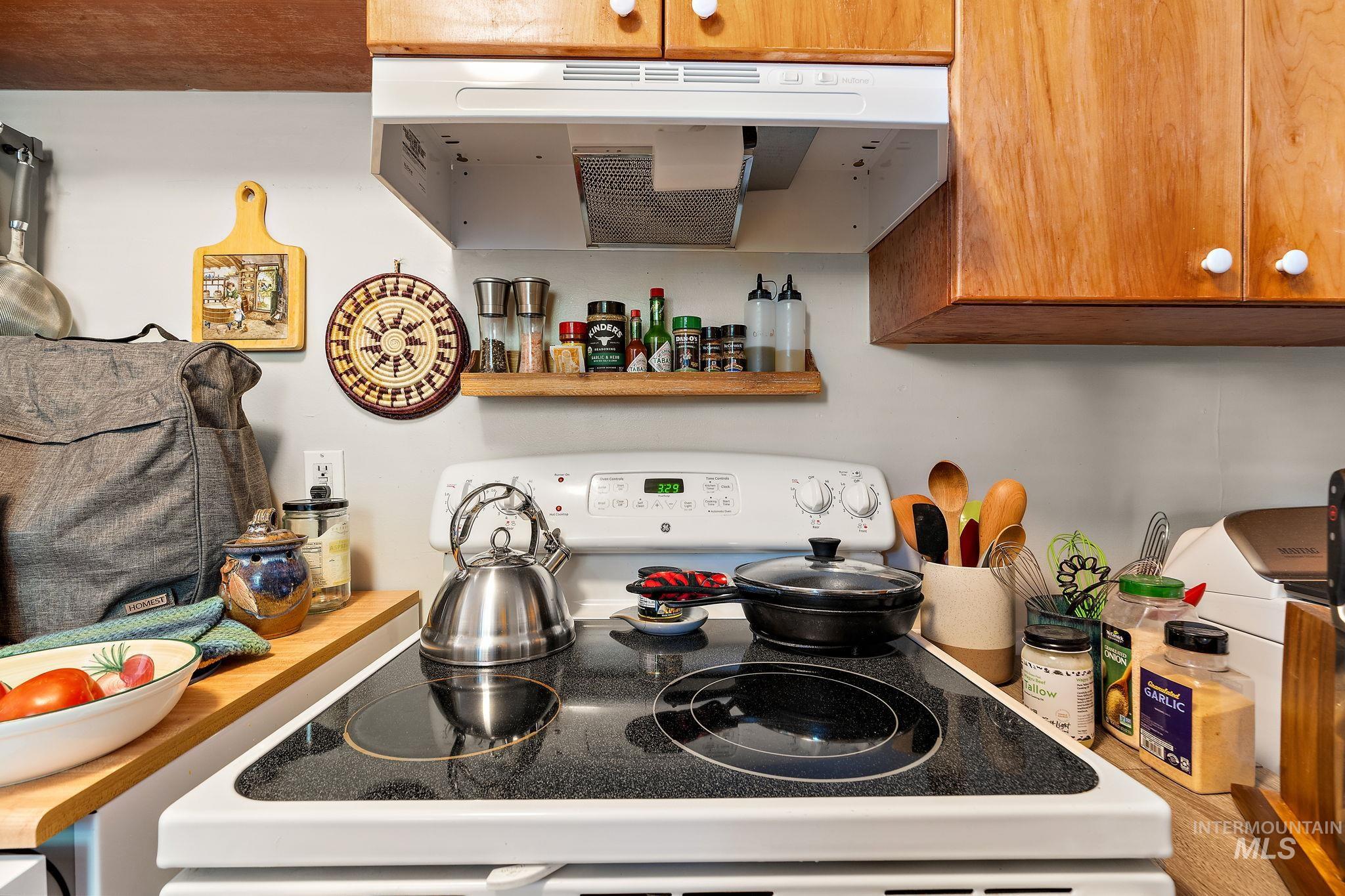 Kitchen featuring range with electric cooktop, extractor fan, and brown cabinets