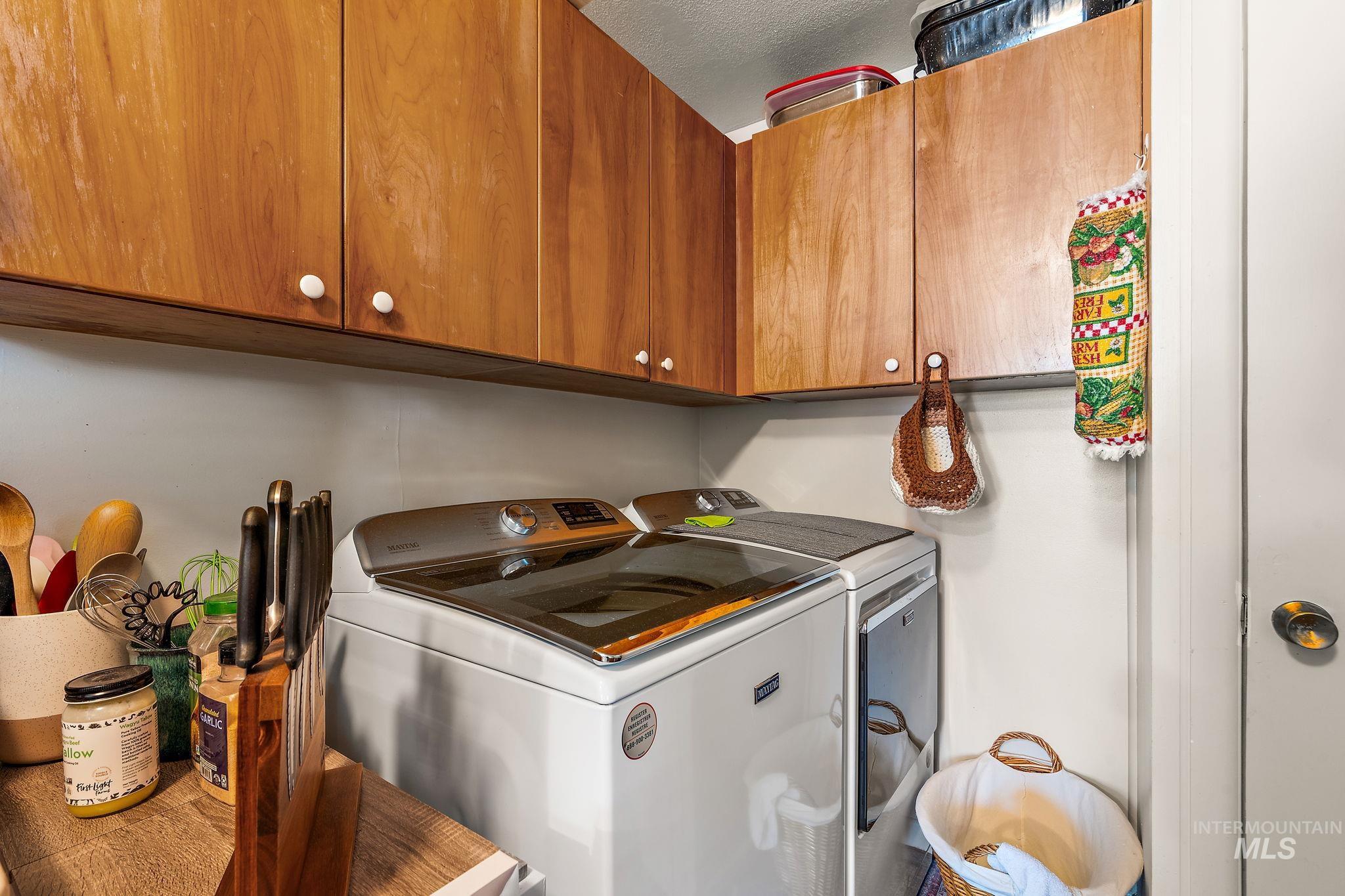 Laundry room with washer and clothes dryer, cabinet space, and a textured ceiling