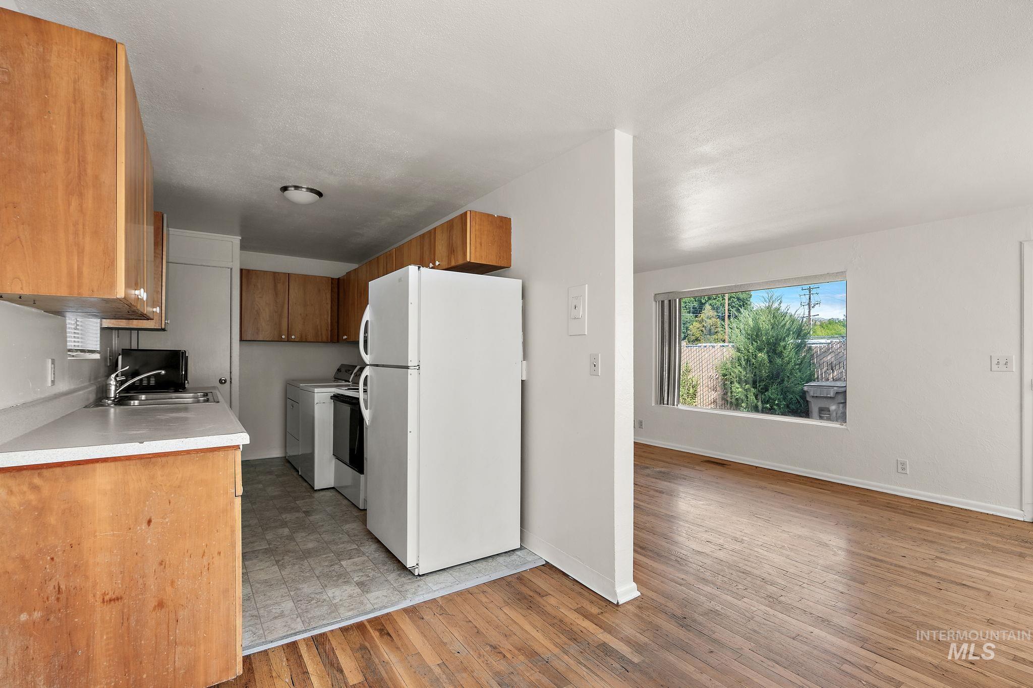 Kitchen featuring freestanding refrigerator, light countertops, light wood finished floors, brown cabinets, and electric range