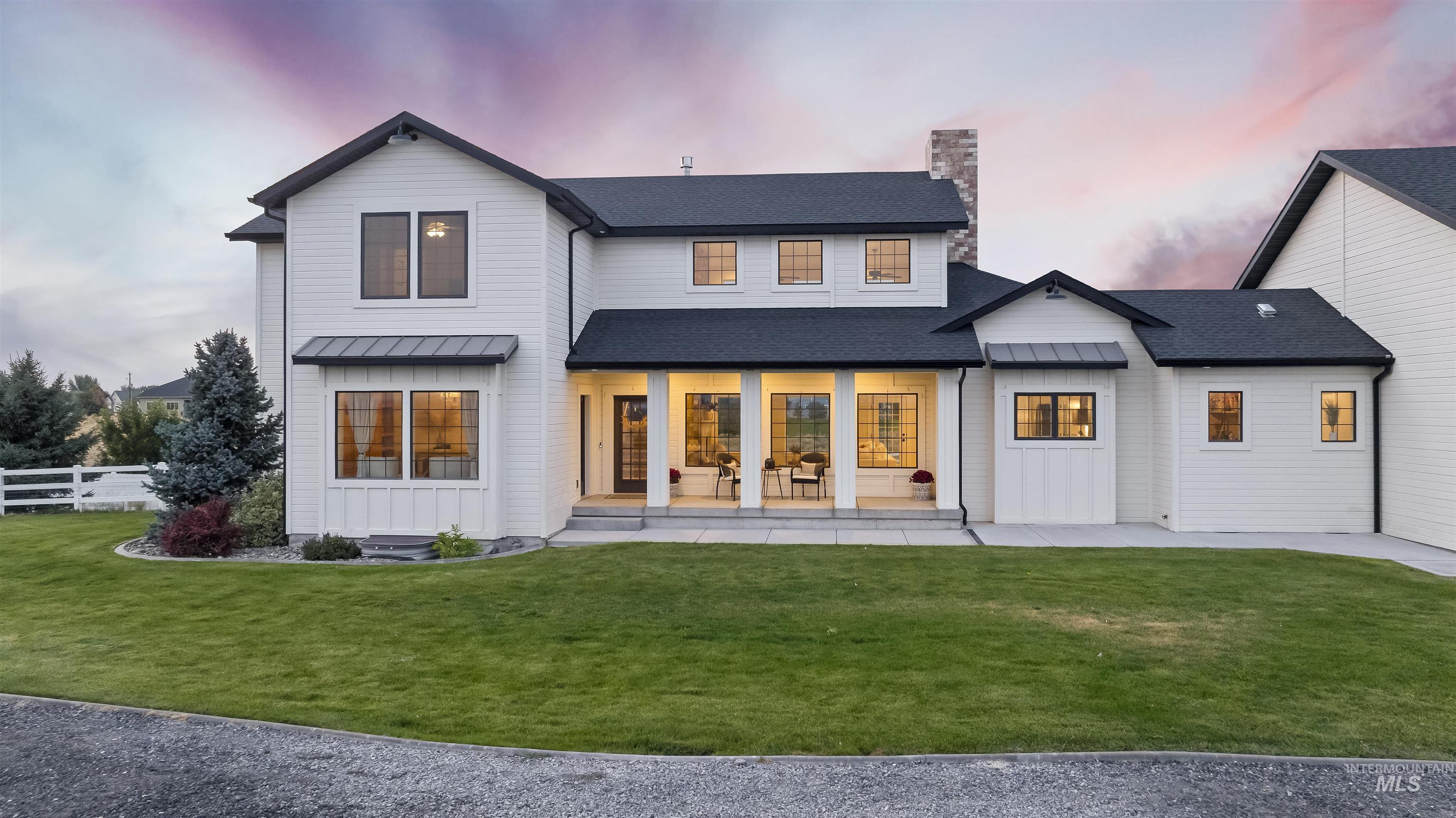 Back of property at dusk featuring a porch, a standing seam roof, board and batten siding, a chimney, and roof with shingles