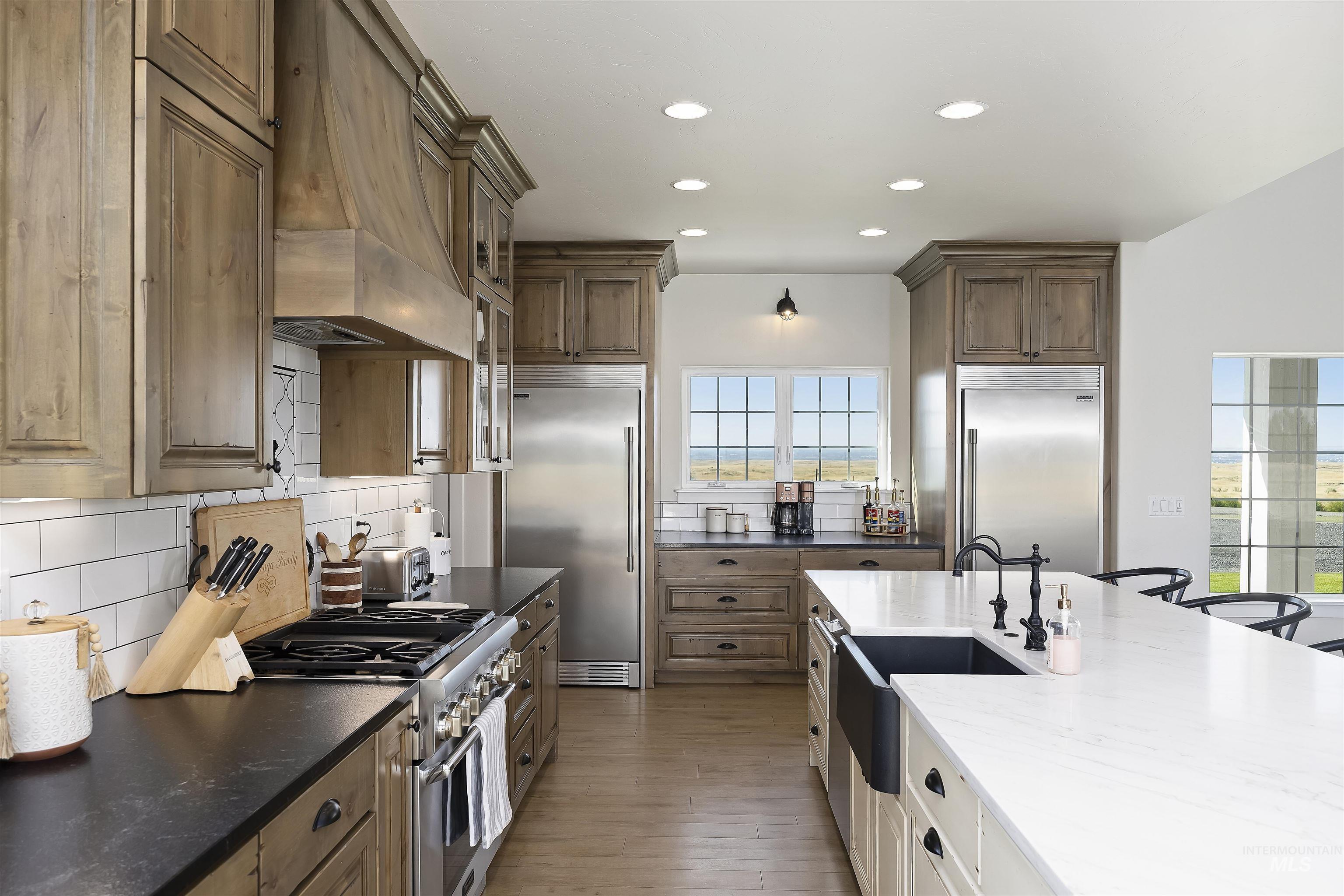 Kitchen featuring backsplash, high quality appliances, dark stone counters, custom range hood, and recessed lighting