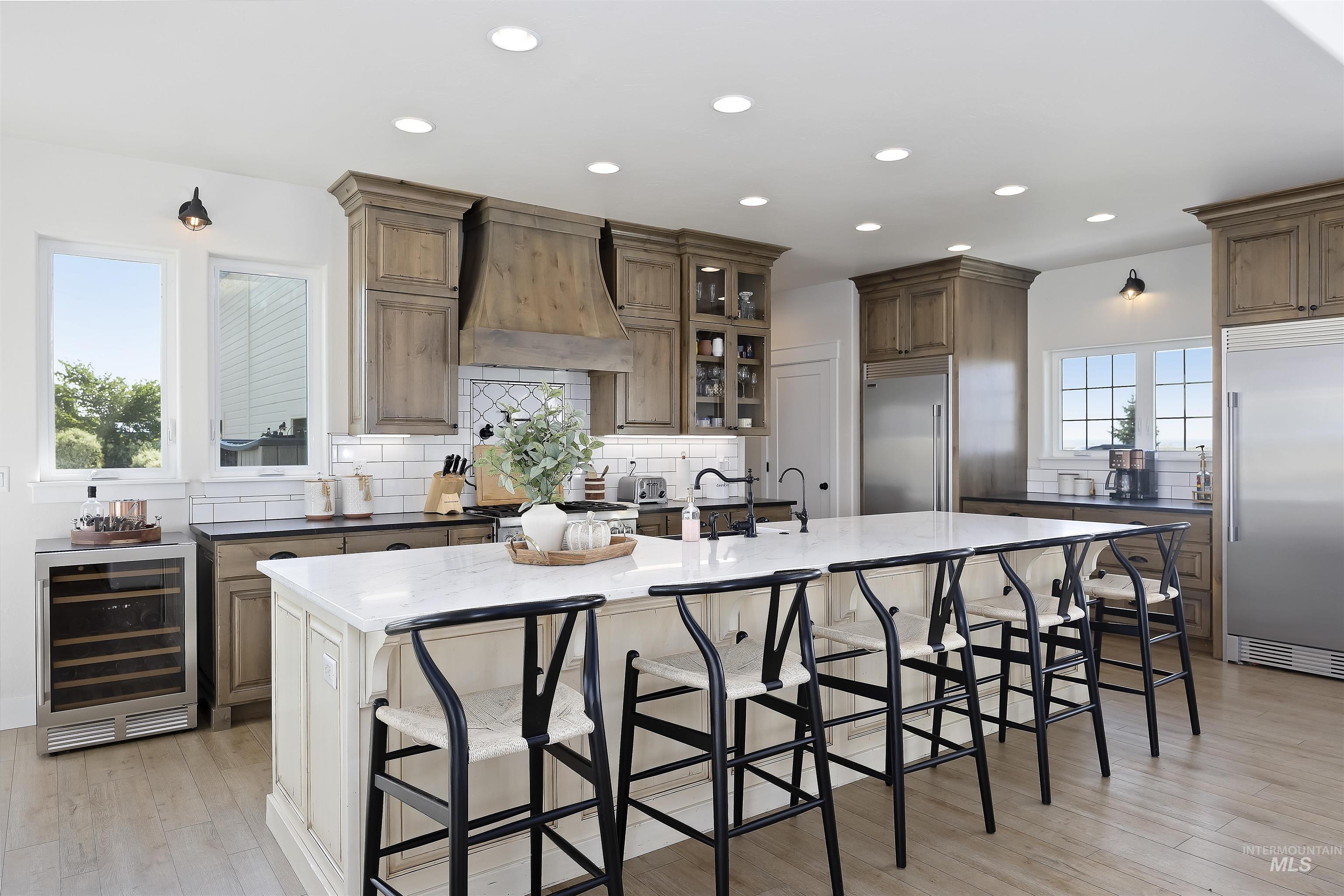 Kitchen featuring backsplash, a breakfast bar area, a large island with sink, built in refrigerator, and beverage cooler