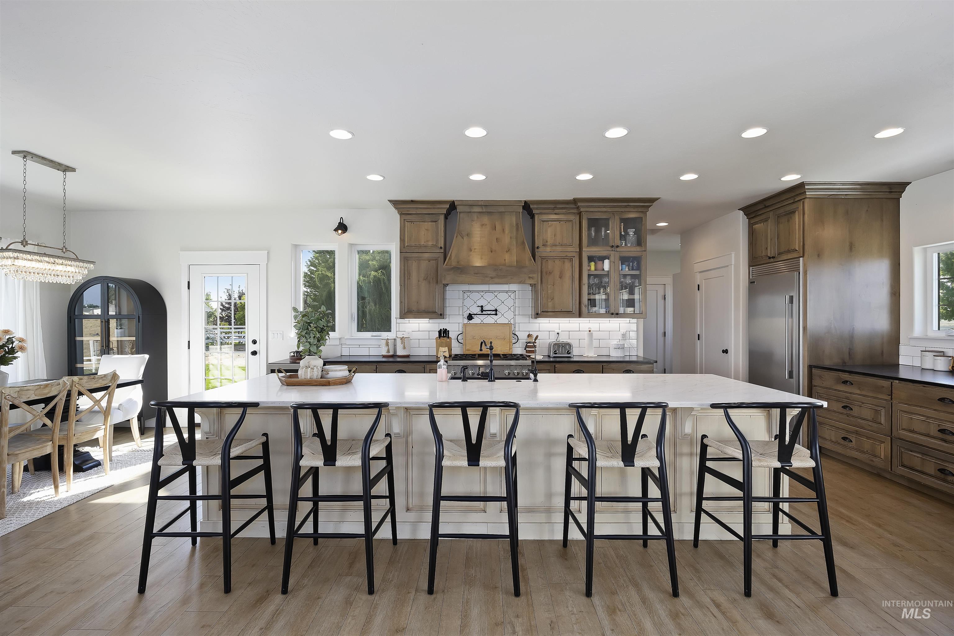 Kitchen featuring a large island, tasteful backsplash, a kitchen bar, recessed lighting, and light wood-style floors
