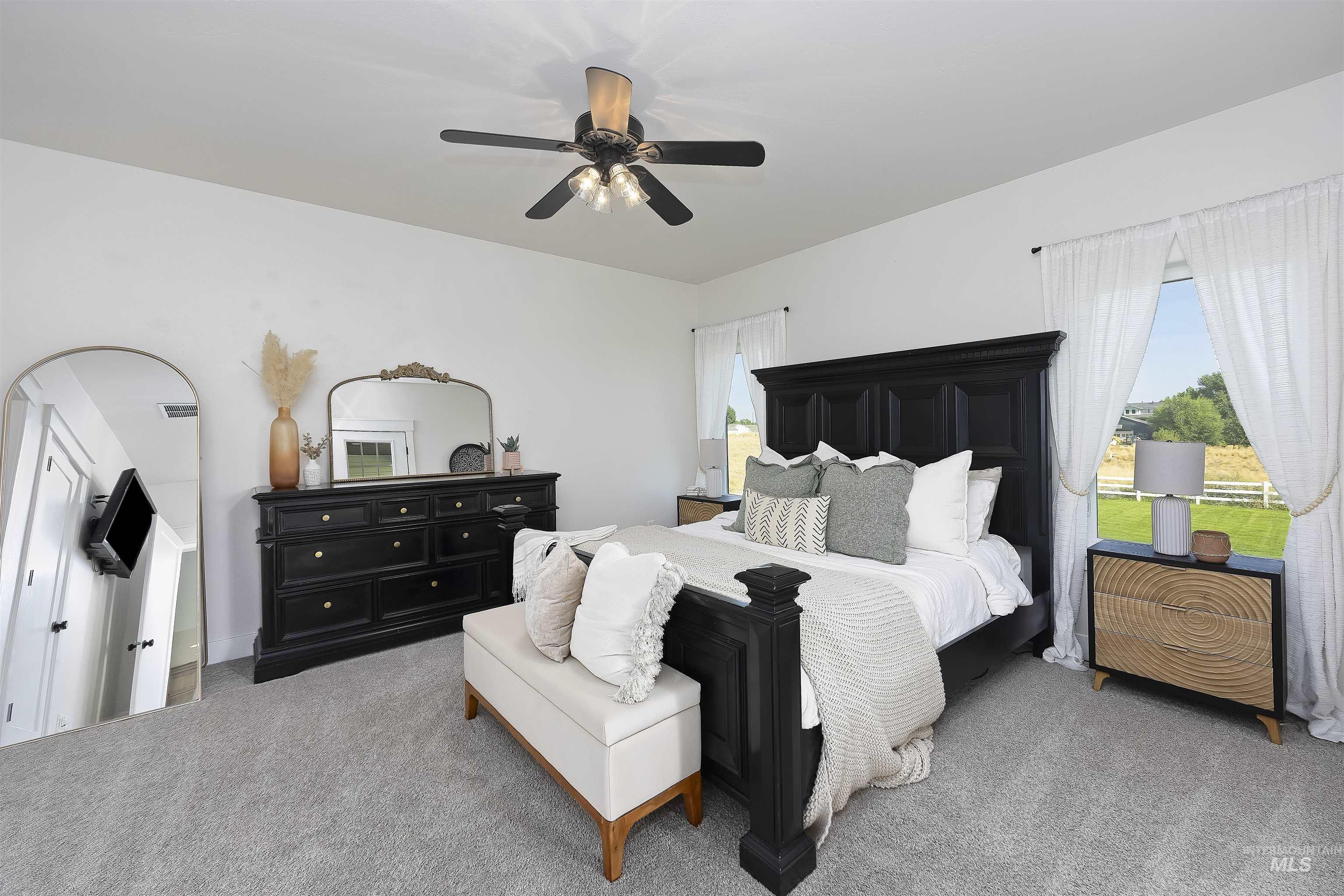 Carpeted bedroom featuring multiple windows and ceiling fan