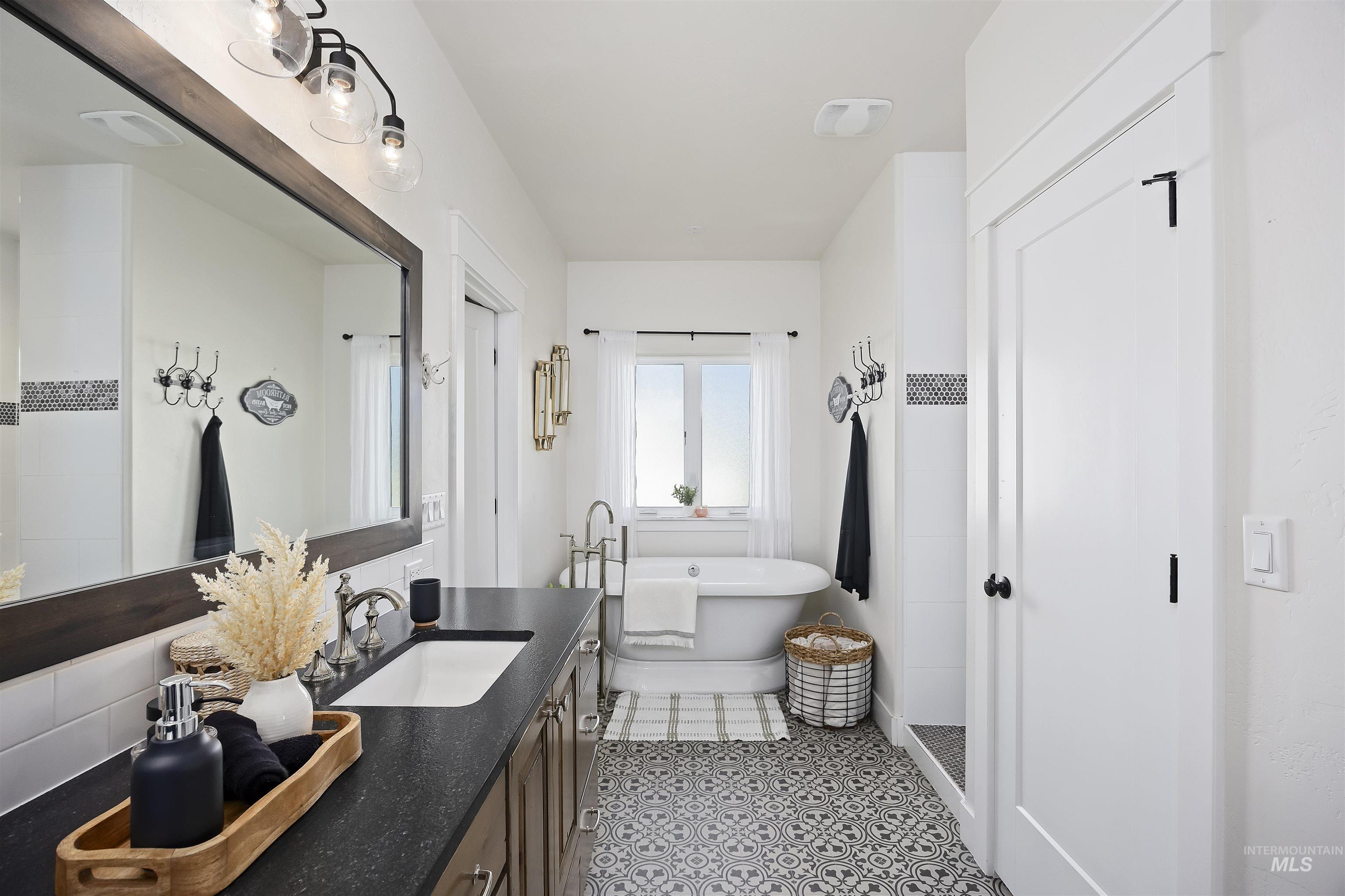 Full bathroom with vanity, a freestanding bath, walk in shower, and light tile patterned floors