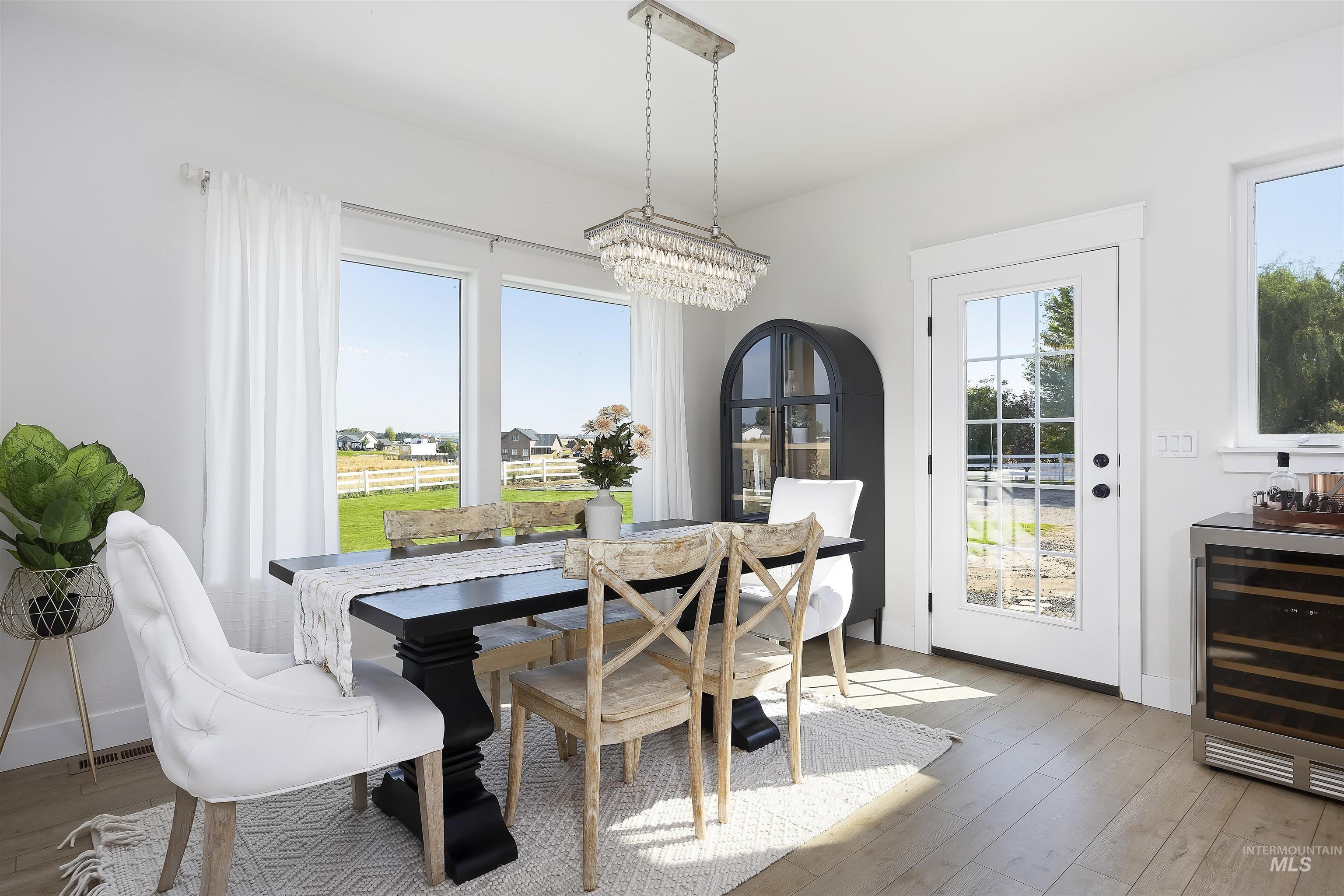 Dining room with beverage cooler, light wood-style floors, and a chandelier
