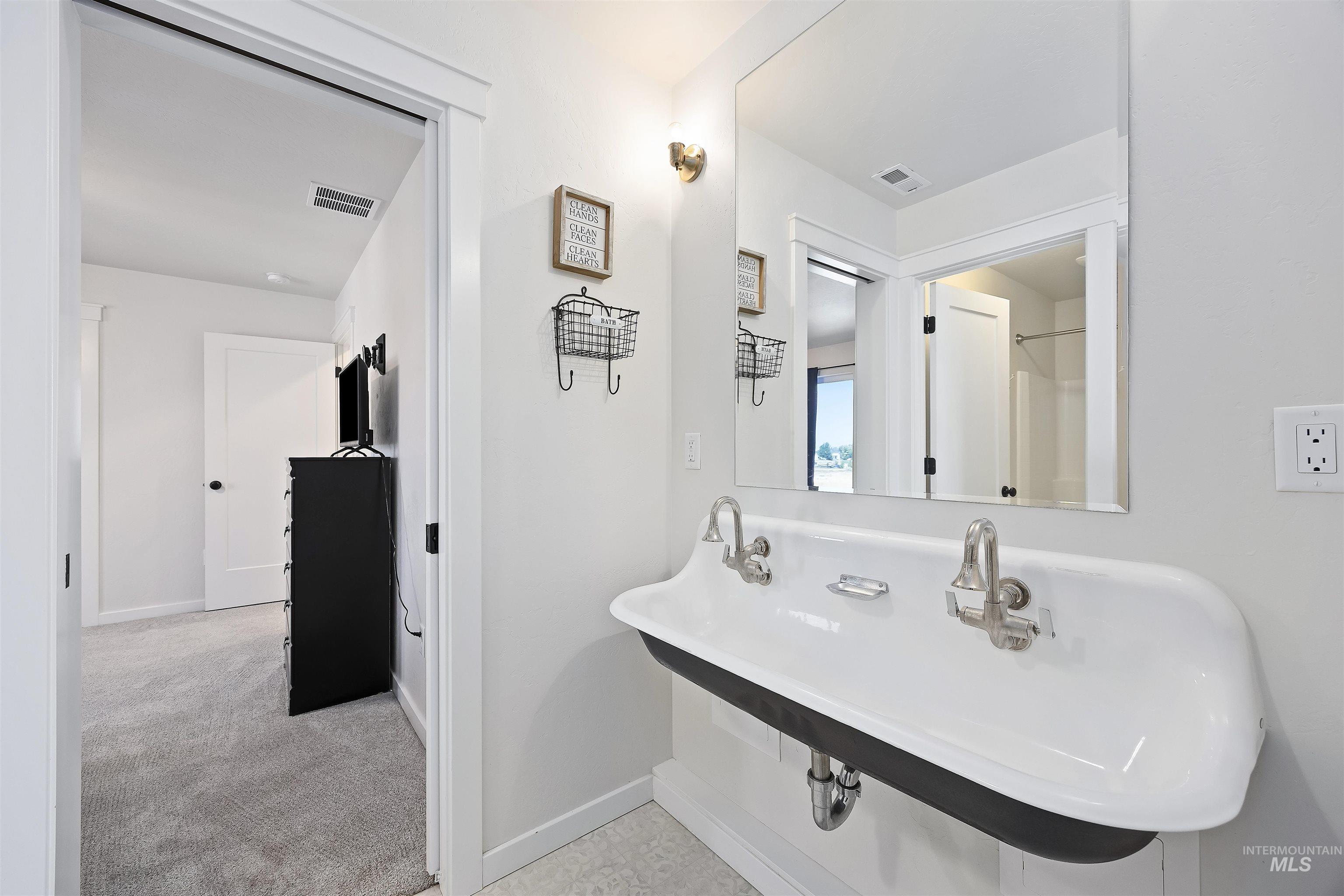 Full bath with a sink and baseboards
