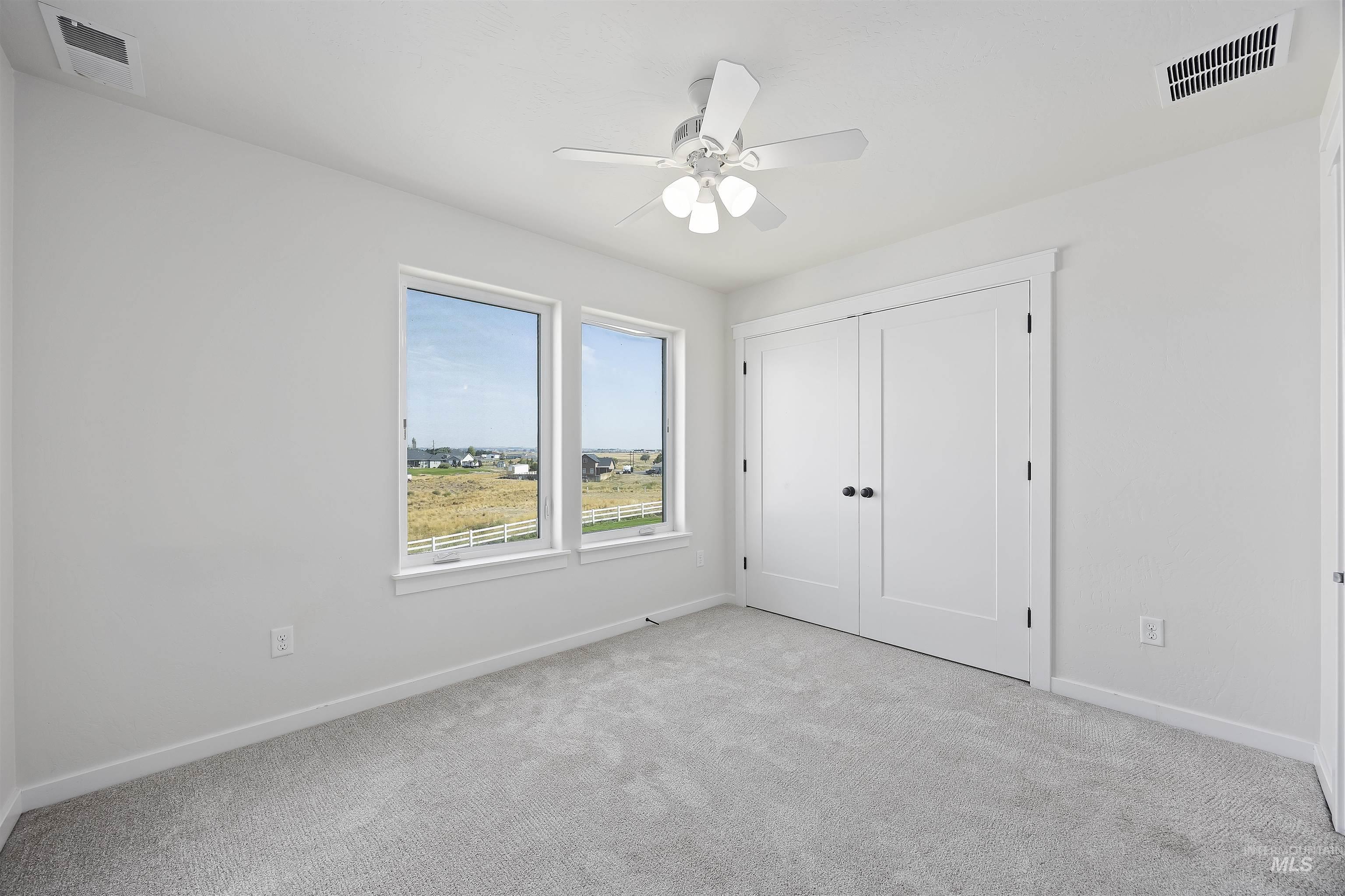 Unfurnished bedroom with light colored carpet, a closet, and a ceiling fan
