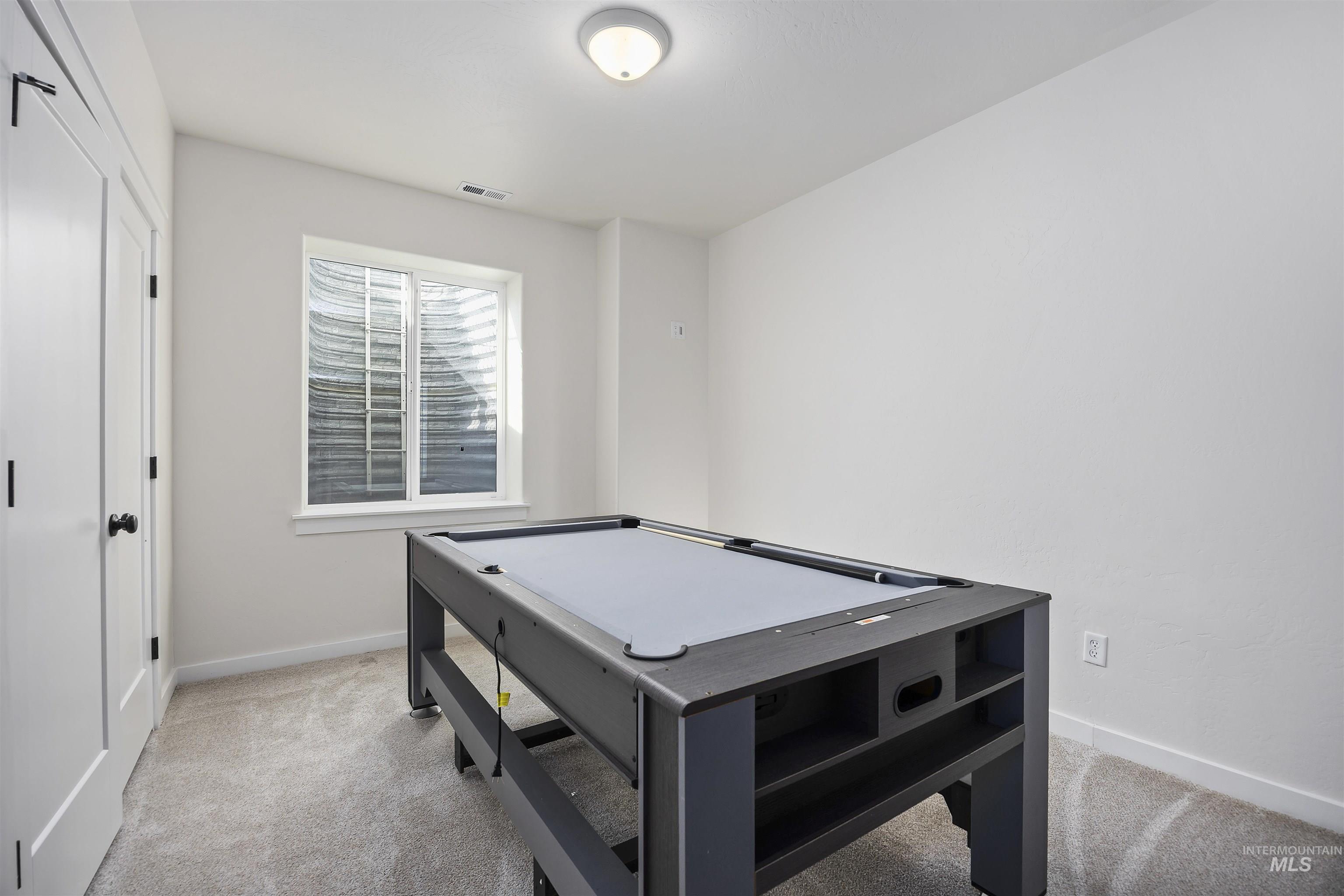 Recreation room with light colored carpet and baseboards