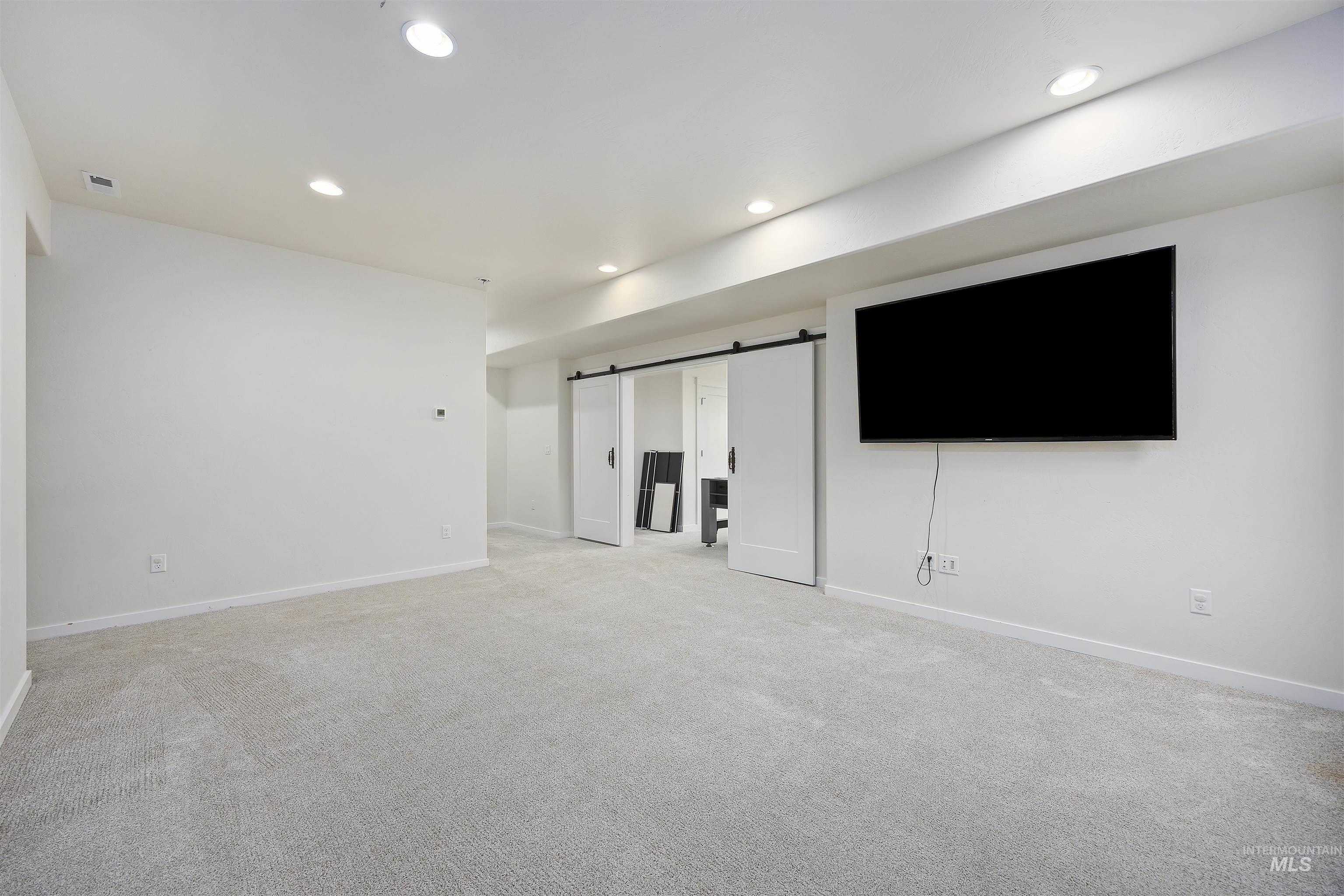 Below grade area with a barn door, recessed lighting, and light colored carpet
