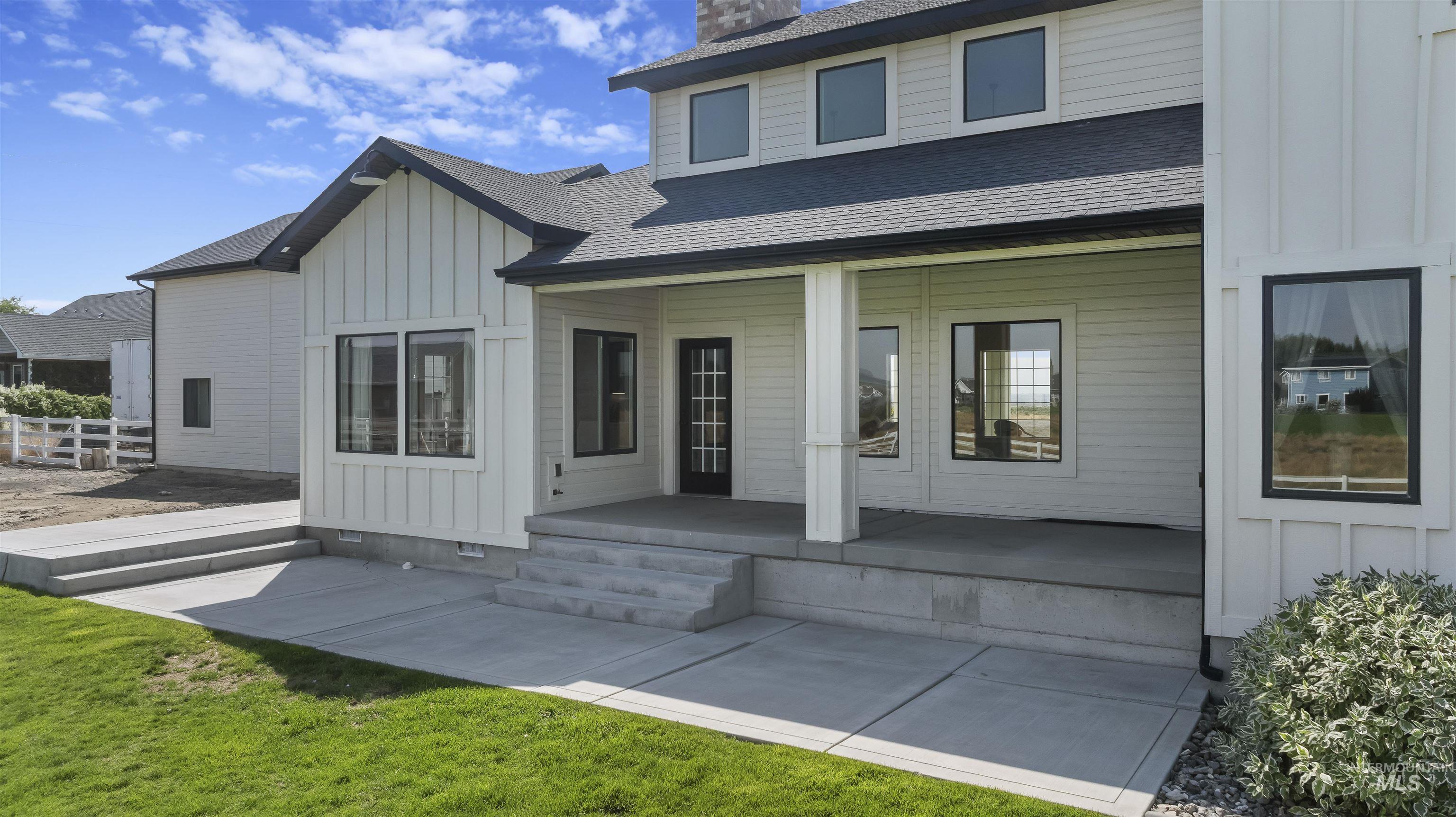 Back of property with board and batten siding, a shingled roof, and a patio