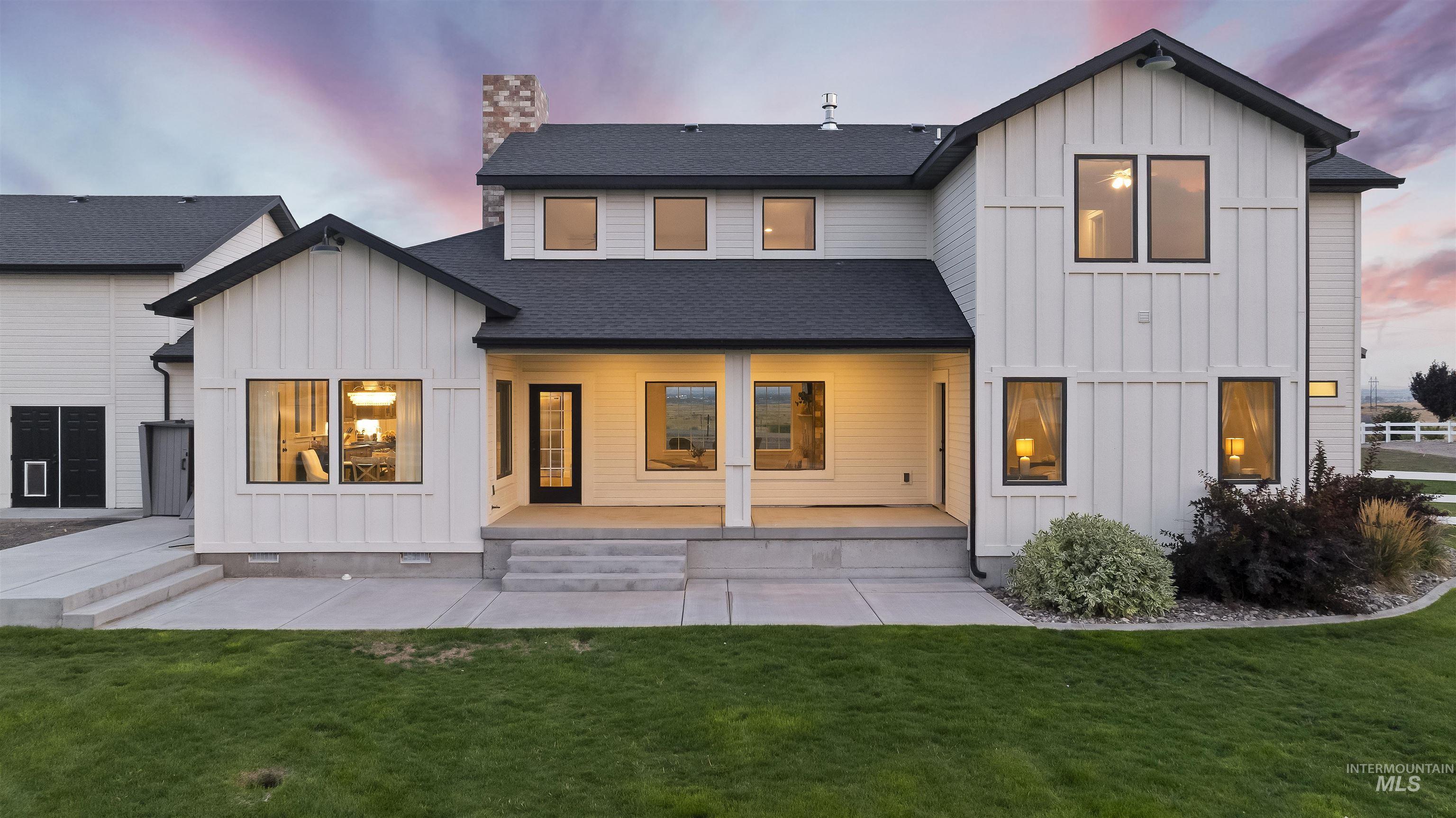 Back of property at dusk featuring board and batten siding, a lawn, a chimney, and a shingled roof
