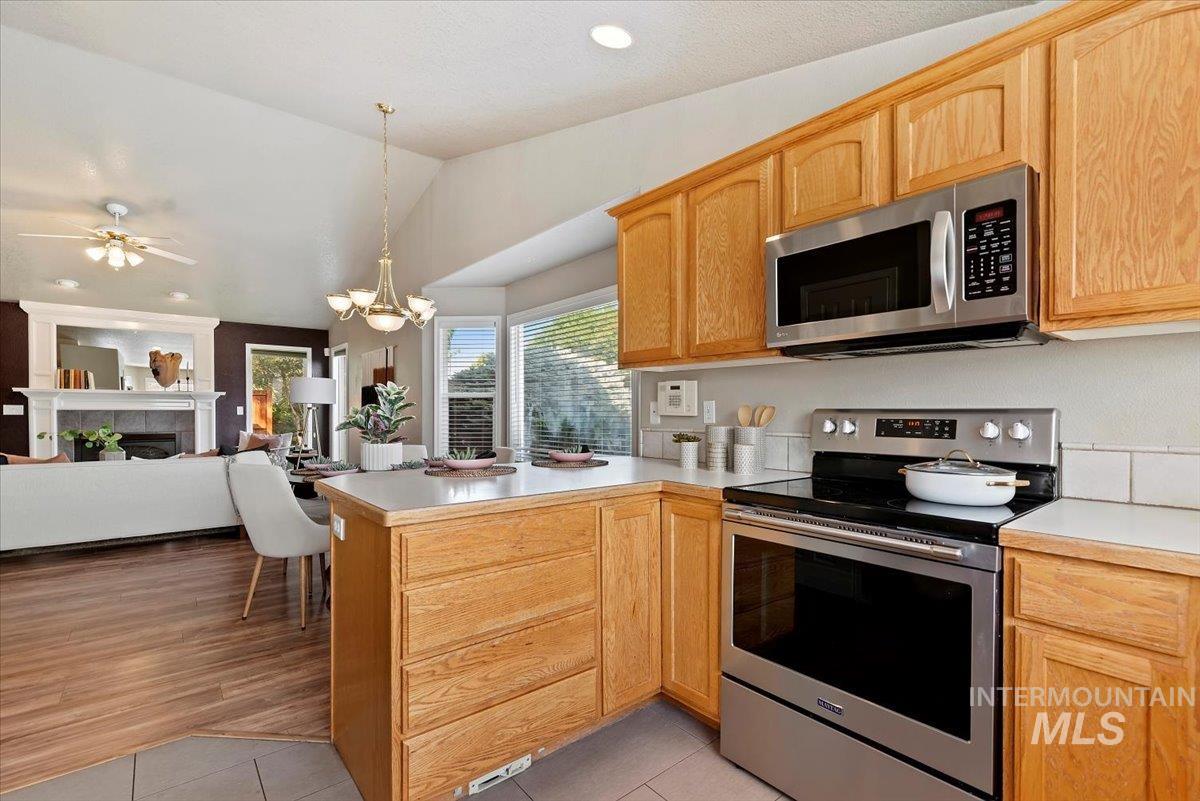 Kitchen featuring stainless steel appliances, light countertops, open floor plan, decorative light fixtures, and a peninsula