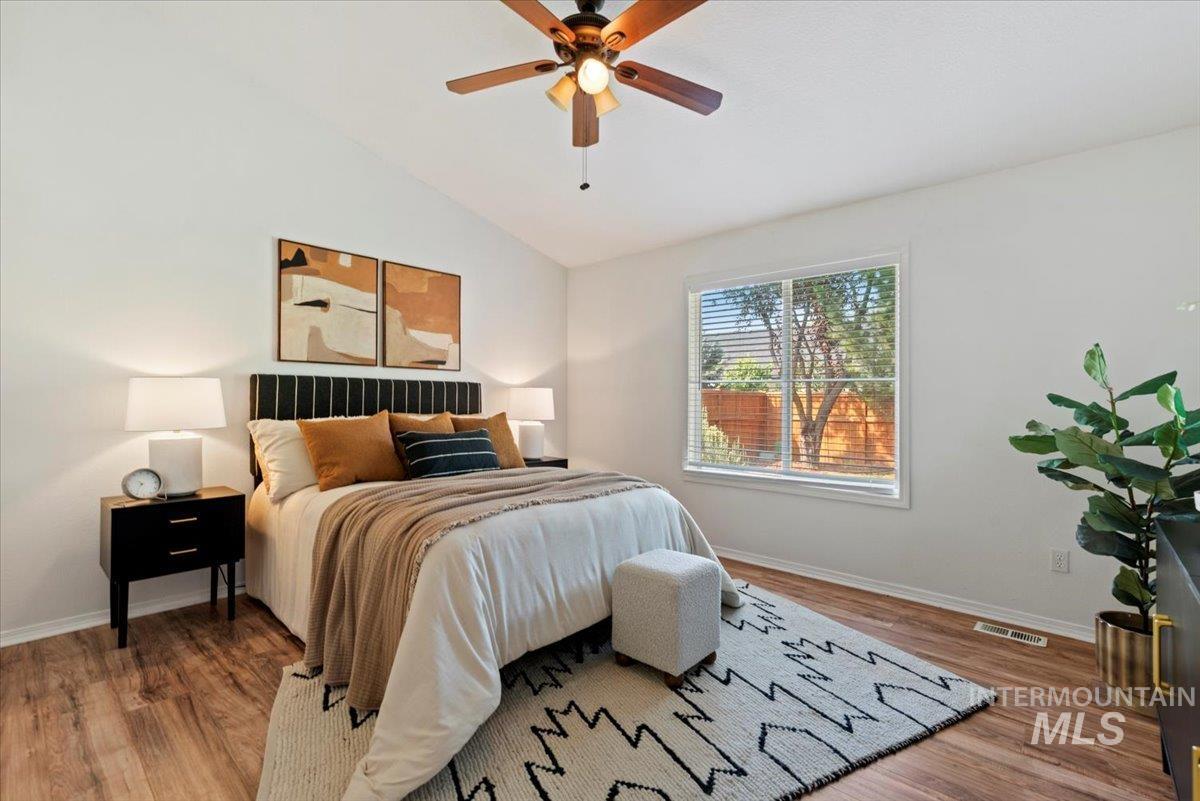 Bedroom featuring lofted ceiling, wood finished floors, and a ceiling fan