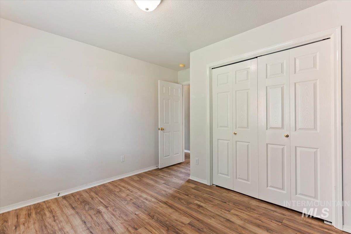 Unfurnished bedroom with wood finished floors and a closet