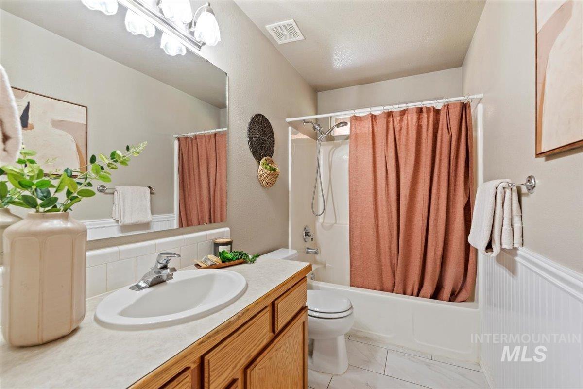 Bathroom with shower / bathtub combination with curtain, vanity, tasteful backsplash, and light tile patterned floors