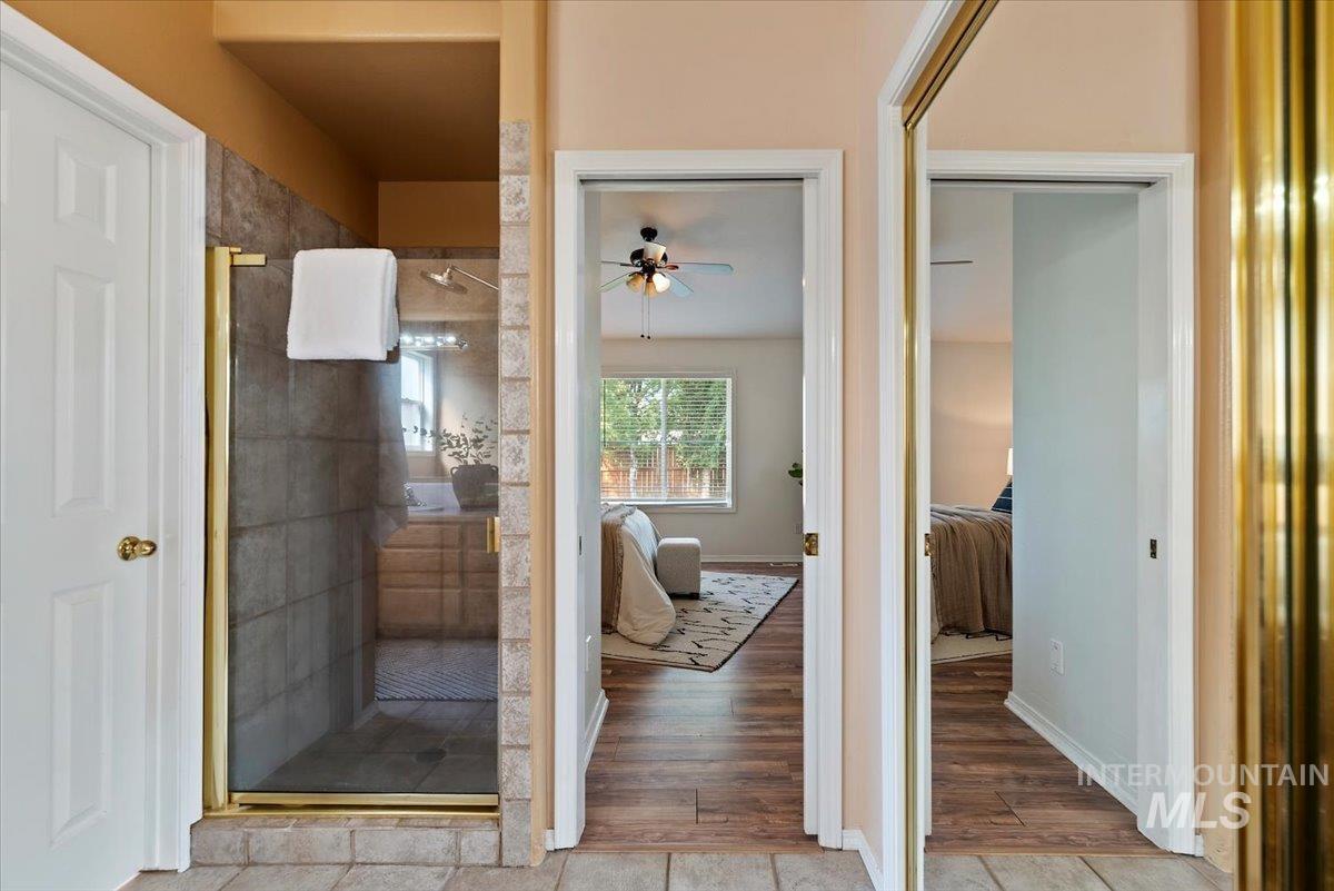 Ensuite bathroom featuring a stall shower, a ceiling fan, and wood finished floors