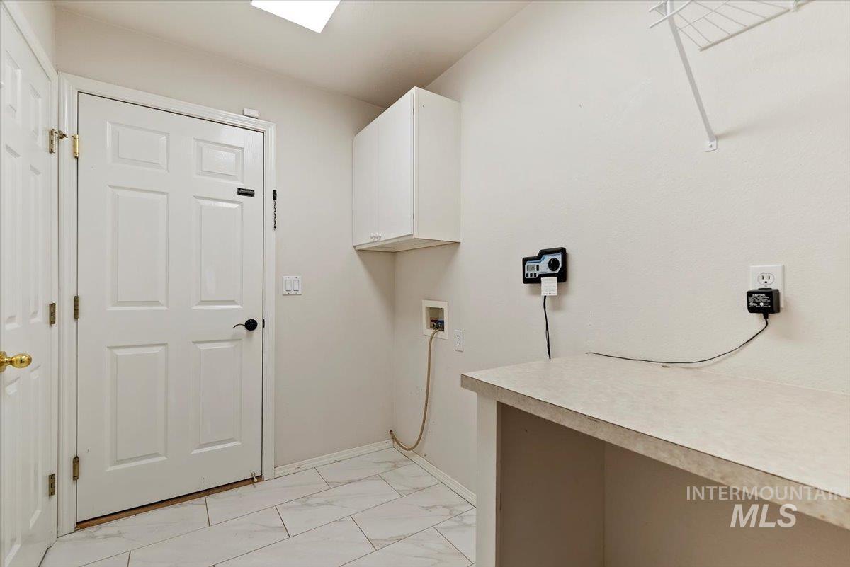 Washroom featuring washer hookup, light marble finish floors, and cabinet space